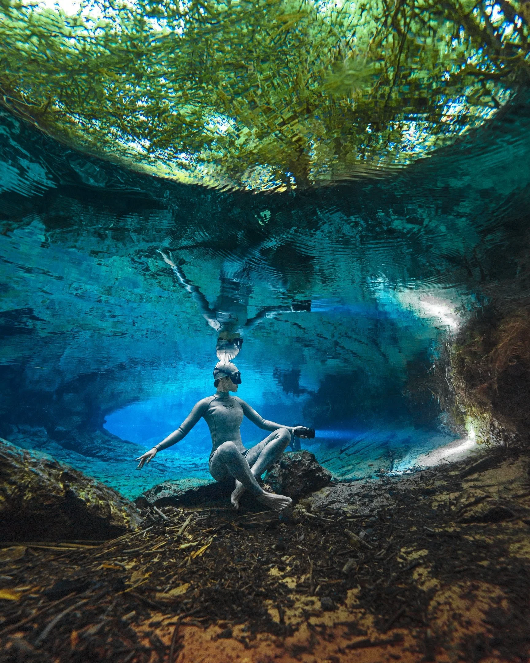 Freediver practising relaxed underwater movement beneath the surface in clear blue water