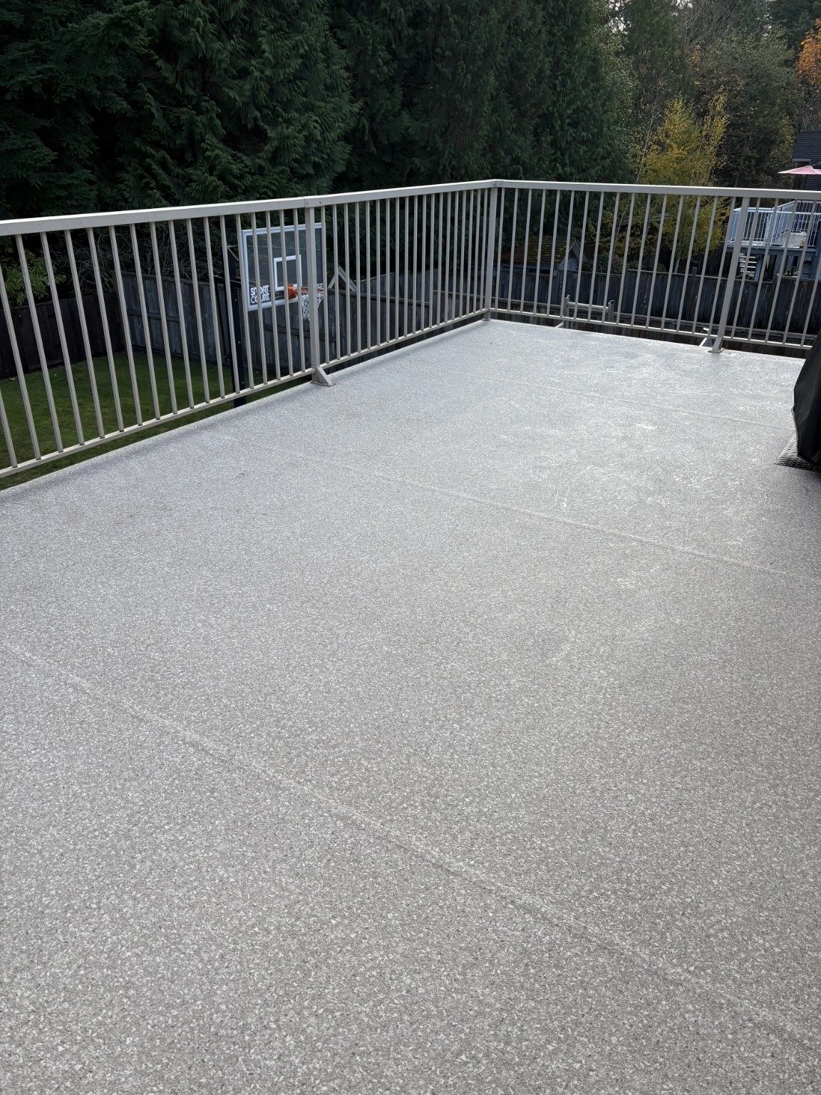 After: completed grey vinyl deck with metal railings overlooking the yard.