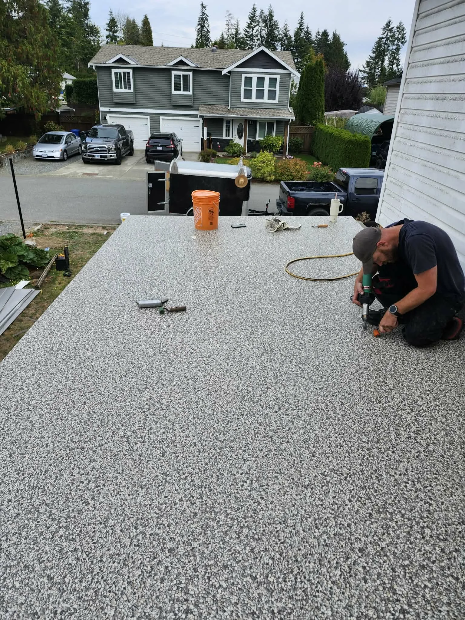 Grey deck surface beside a house, overlooking a residential driveway.