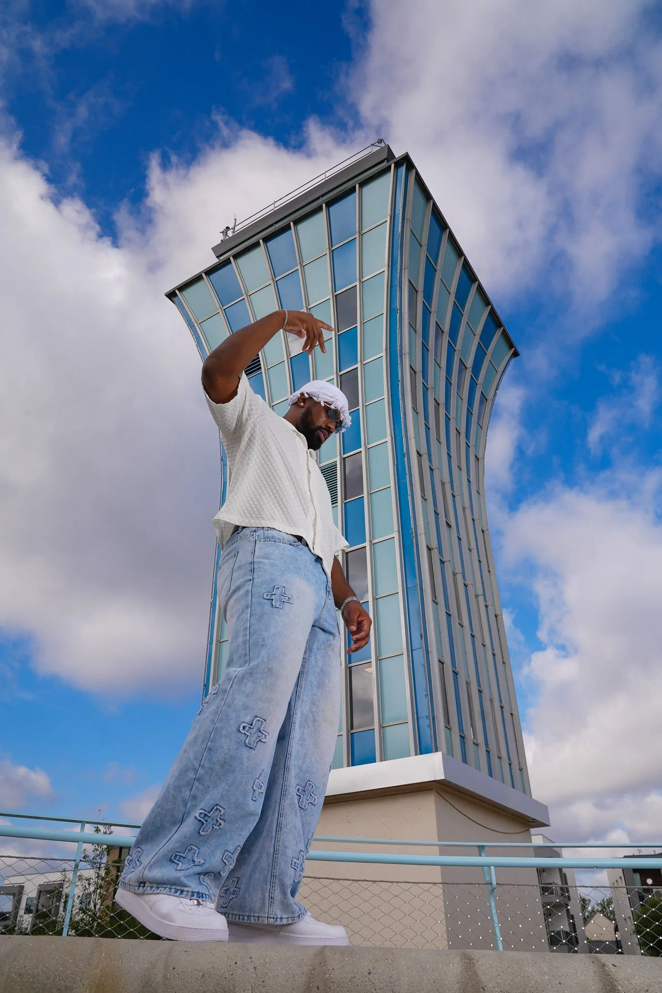 “Jacob Berry modeling a white outfit on an outdoor staircase beneath a bright blue sky.”