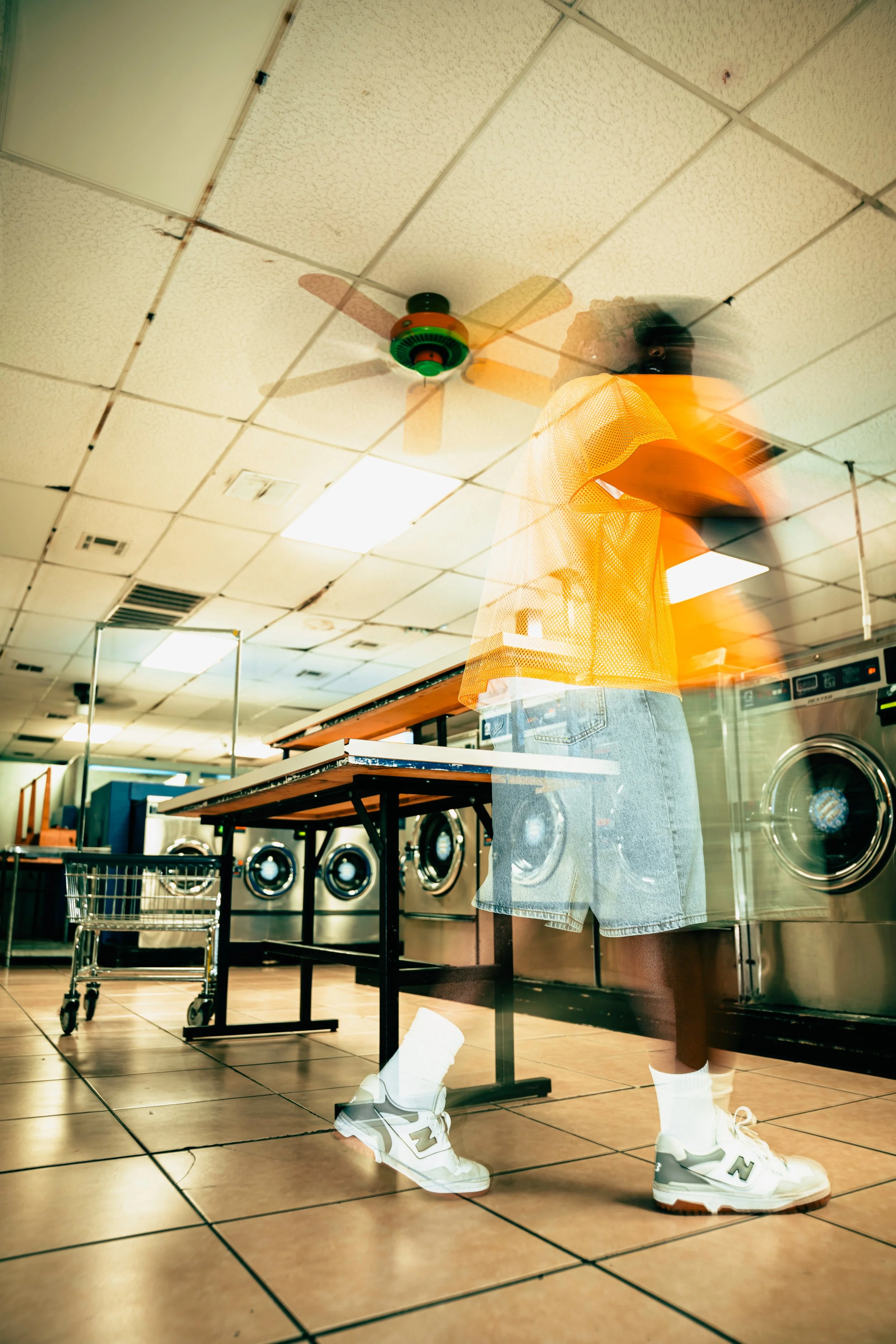 Laundromat: “Jacob Berry modeling an orange mesh jersey and denim shorts inside a laundromat, captured with motion blur.”