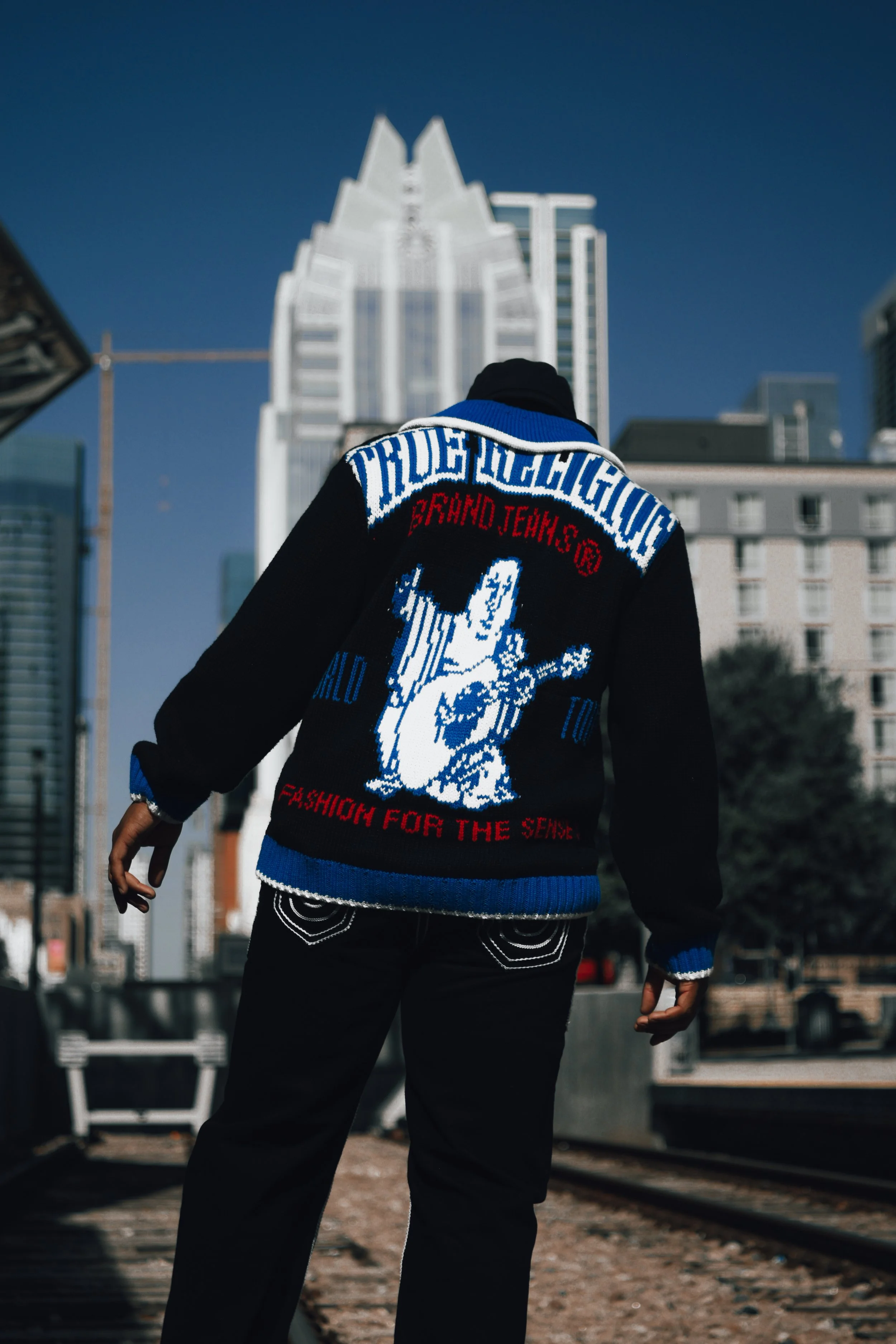 True Religion: “Jacob Berry modeling a black, blue, and white True Religion knit jacket with the Austin skyline in the background.”