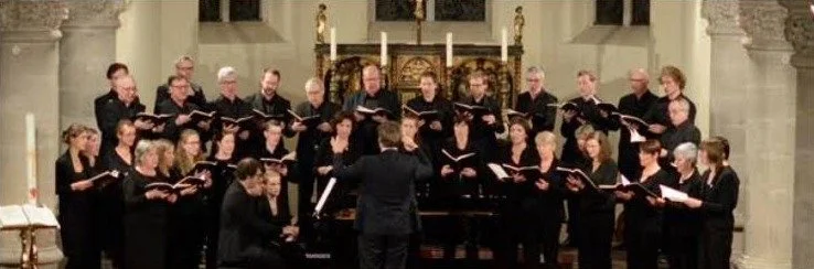 Kamerkoor Roeselare zingt in een kerk, de dirigent staat met de rug naar de camera