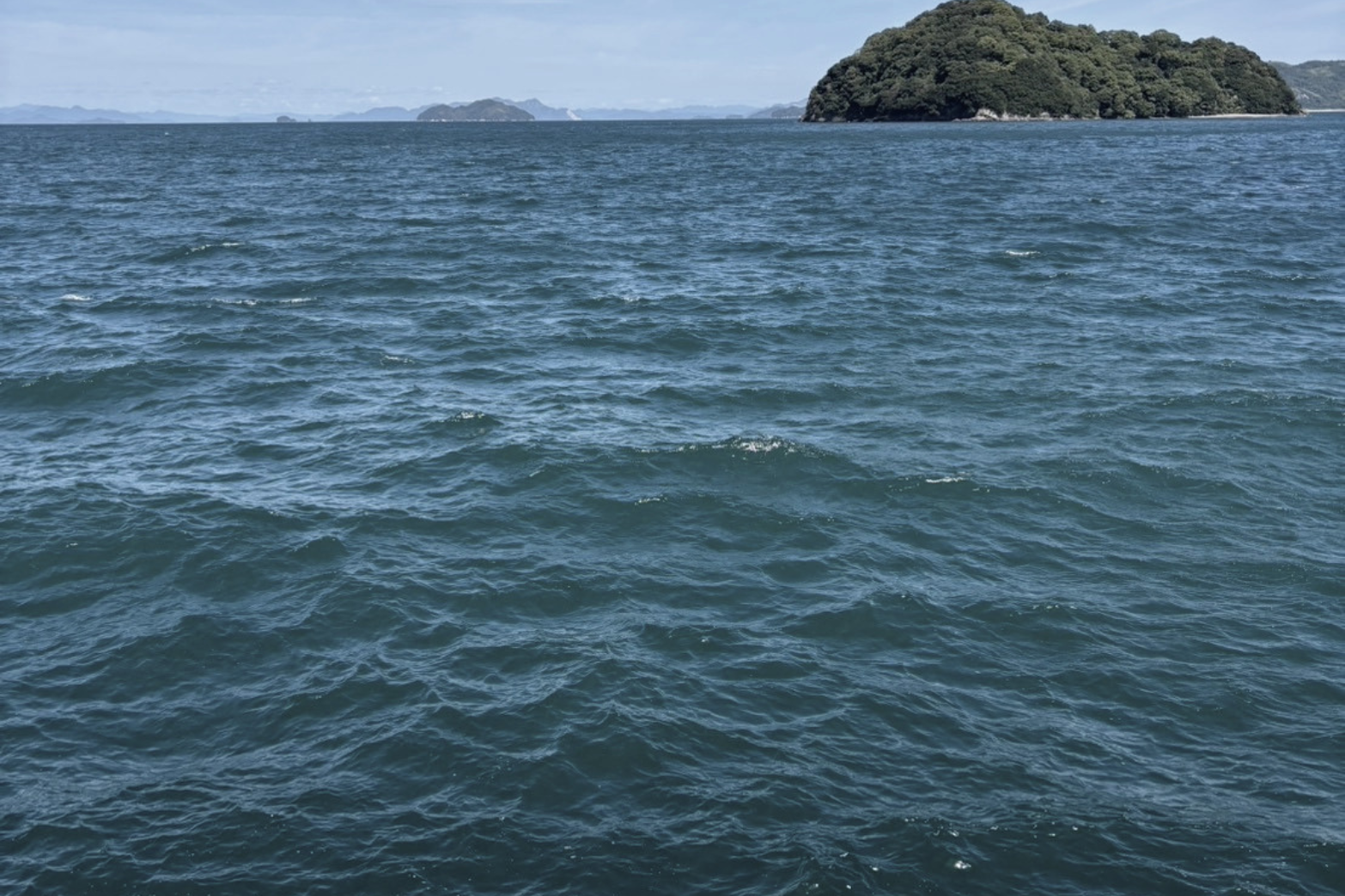 Overlooking the ocean with small islands in the distance under a partly cloudy sky.