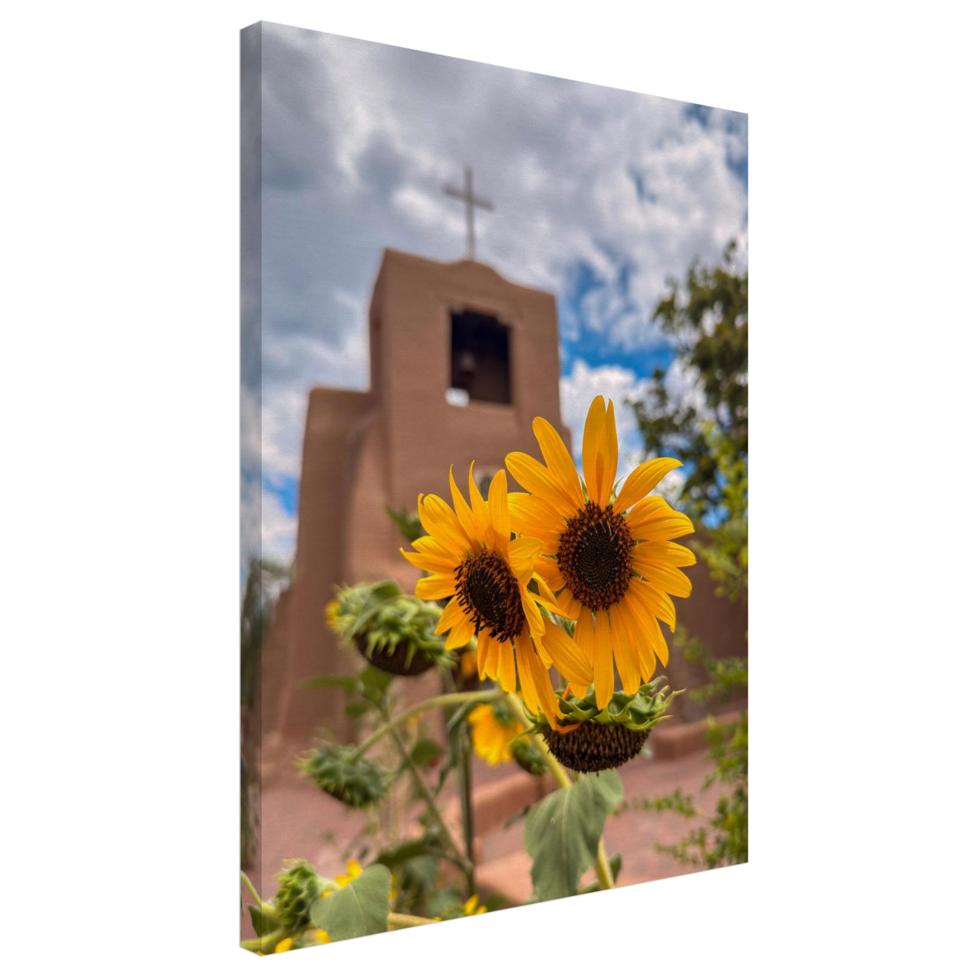 Canvas print of bright sunflowers in front of San Miguel Chapel in Santa Fe, New Mexico. Clouds drift overhead.
