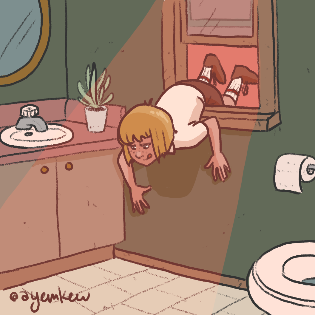 A person with blonde hair is crawling on the bathroom floor looking into a cabinet mirror, with the reflection showing their legs and socks. The bathroom has a sink with a plant and soap on the counter, a toilet paper roll, and a mirror.