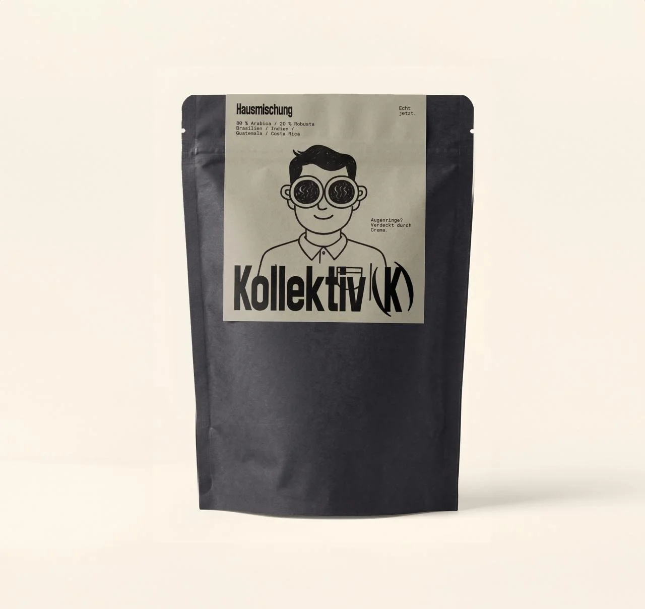 Schwarze Kaffeebohnen Verpackung mit einem grafischen Aufkleber, der eine cartoonartige Figur mit großen Brillengläsern zeigt. Text auf der Verpackung enthält Begriffe wie 'Hausmischung', 'Kollektiv' und weitere Details zur Kaffeezusammensetzung.
