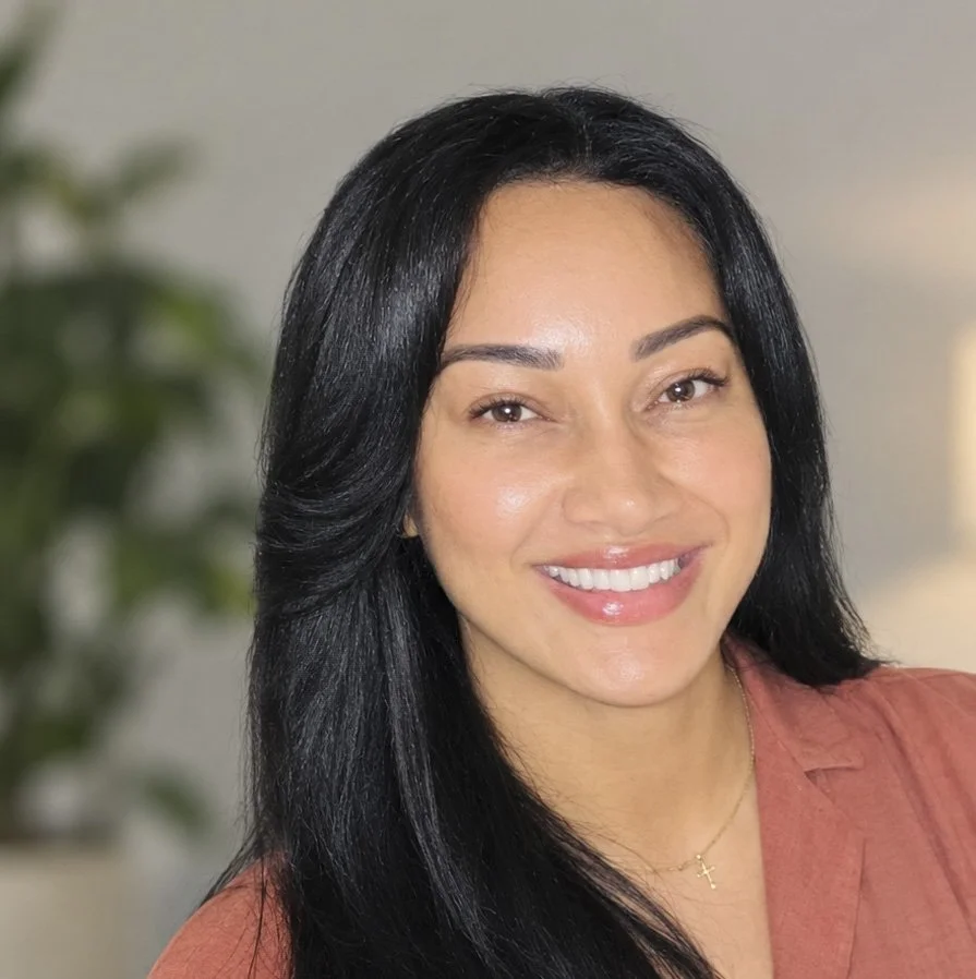 Professional headshot of Shana, Employment Coach, smiling warmly with long dark hair and a soft neutral background, representing approachable, person-centred employment support focused on confidence, skills and meaningful work.