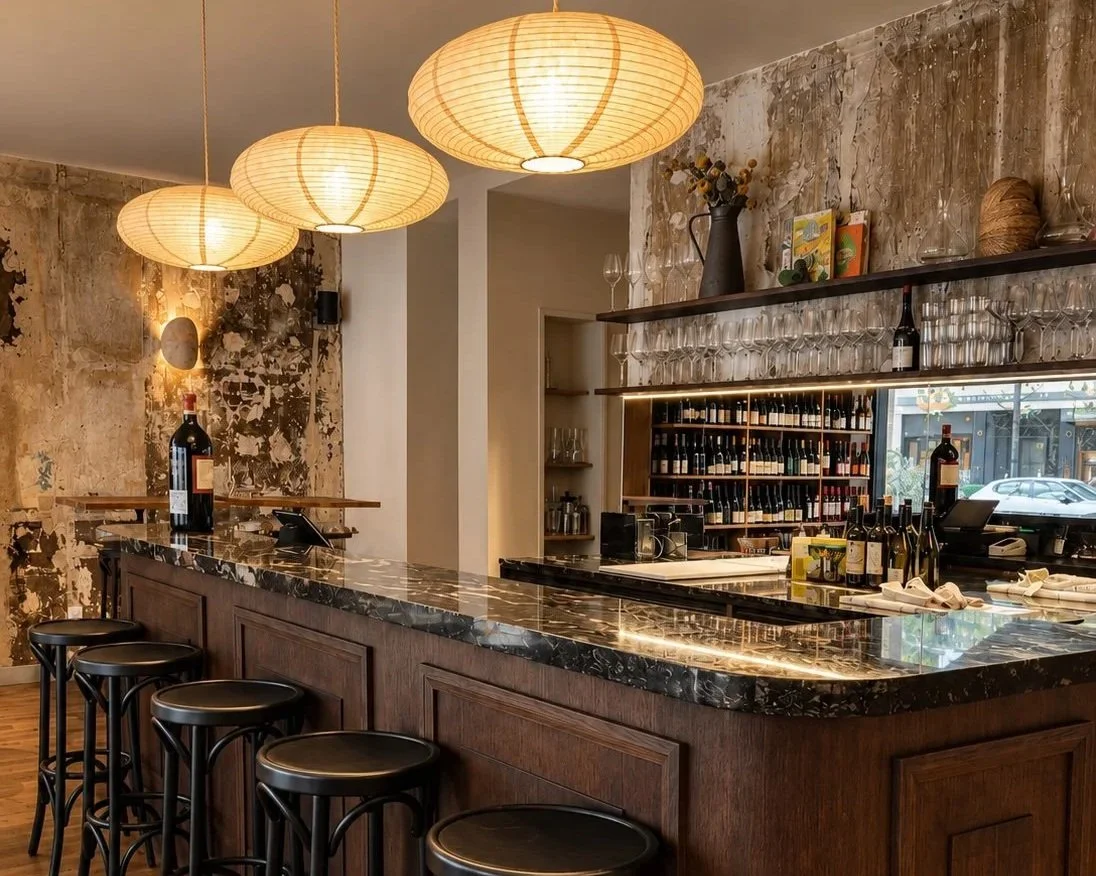 Bar à vins chaleureux à Paris avec comptoir en bois, plateau en marbre et étagères de bouteilles de vin chez fondation bar et cave à vins paris 11eme