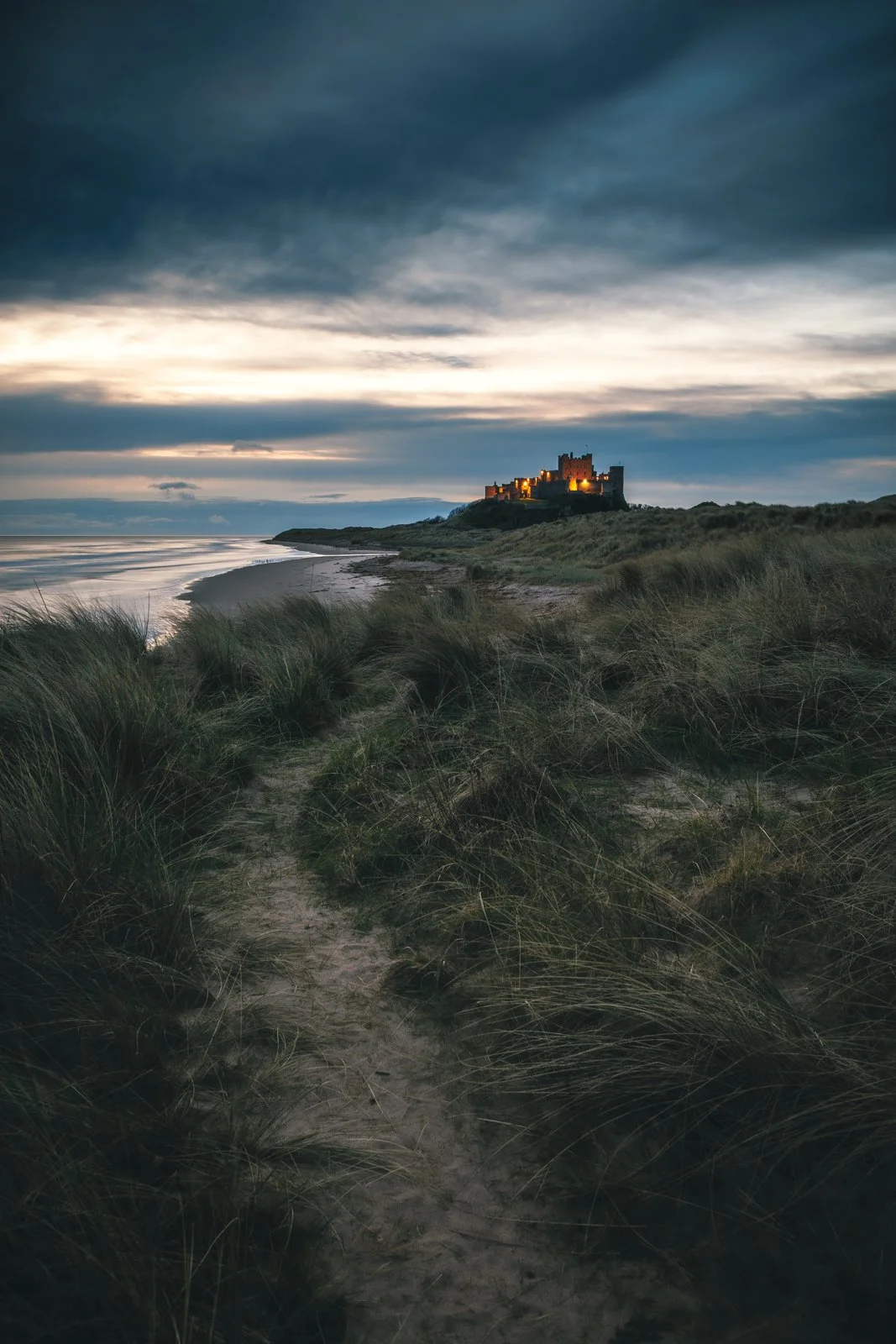 Bamburgh castle with the early morning lights still glowing.