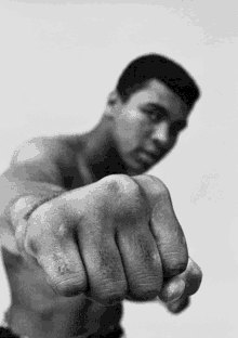 Black and white photo of a man in a fighting stance with his fist extended toward the camera.