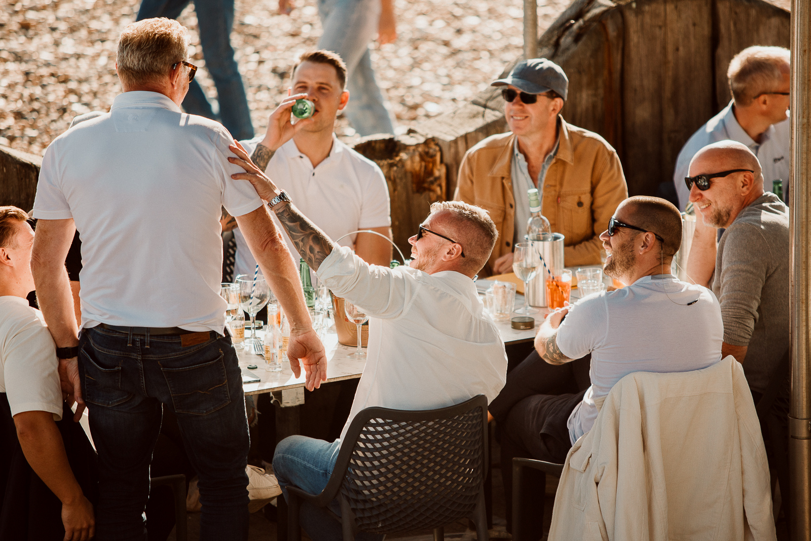 Group of men enjoying drinks and conversation outdoors at a gathering or celebration.