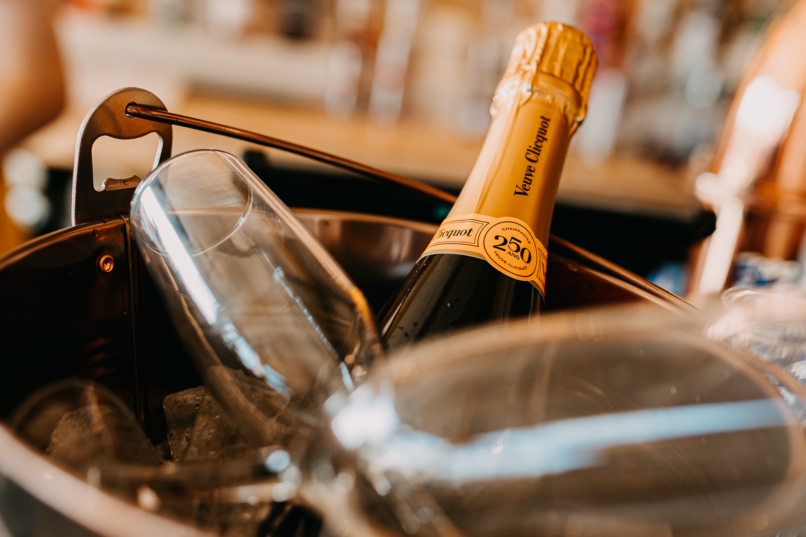 A bottle of Veuve Clicquot champagne in an ice bucket with wine glasses nearby.