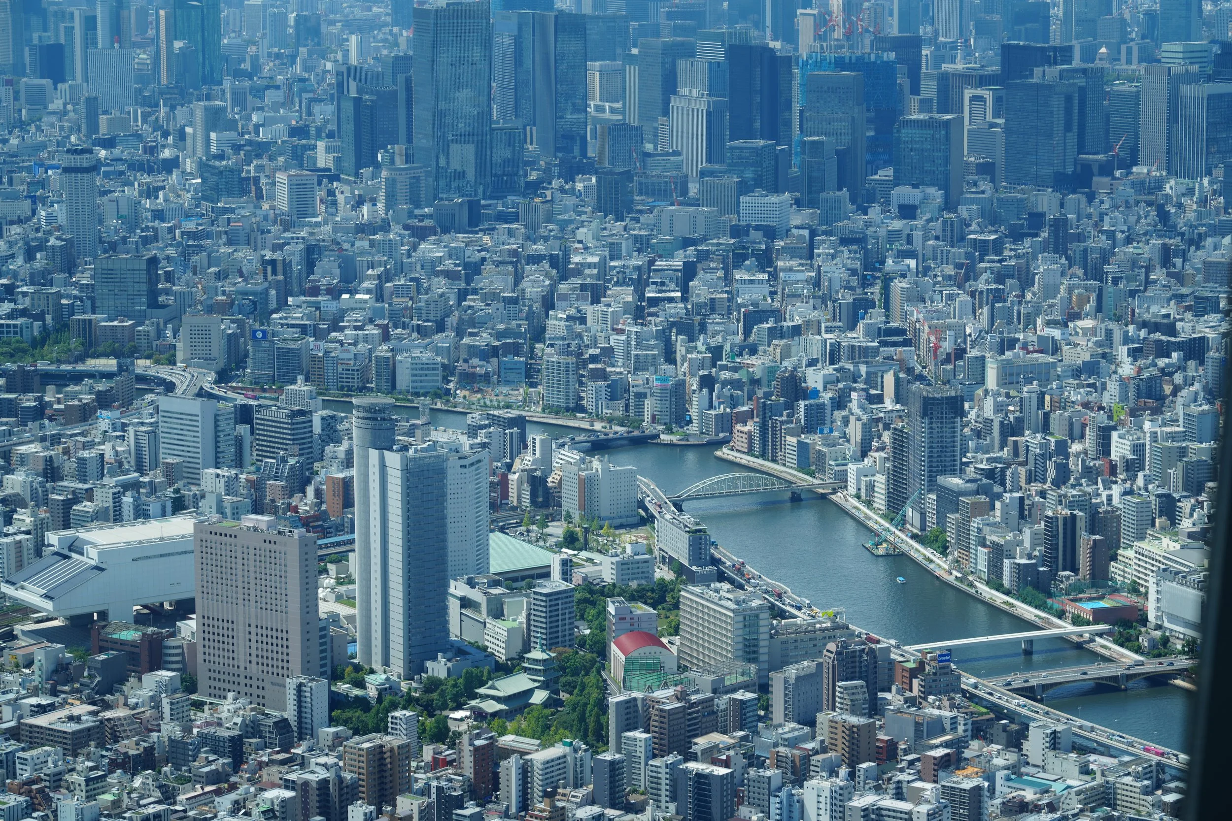 Aerial view of a densely packed cityscape with high-rise buildings, a river running through the city, and bridges crossing the river.