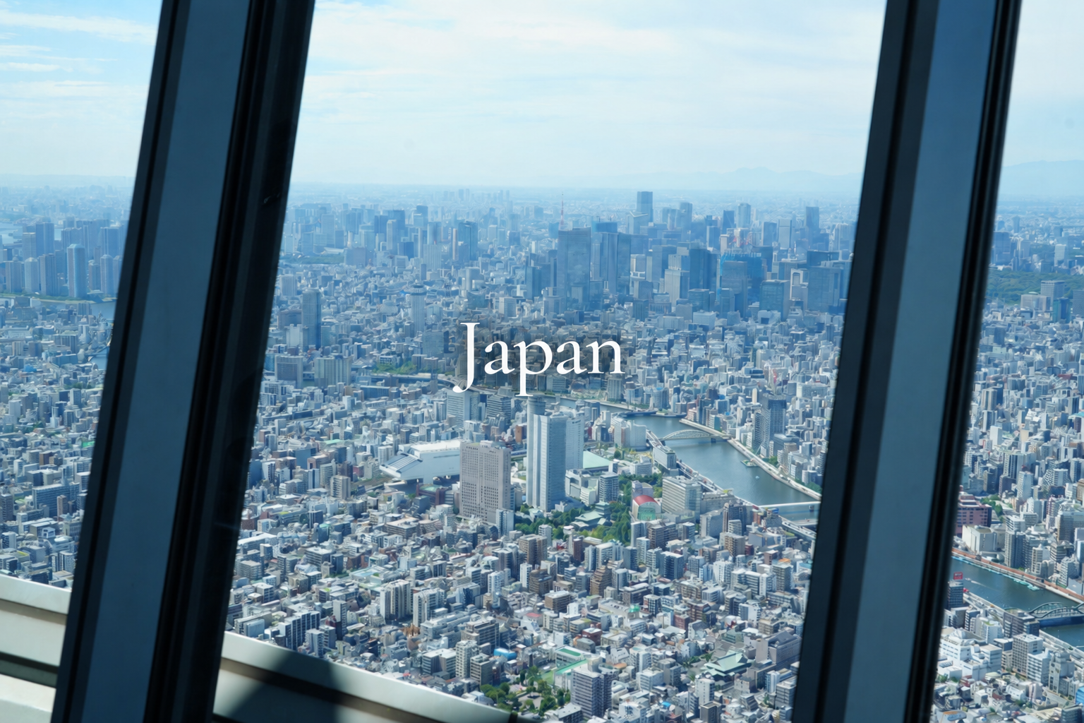 Aerial view of Tokyo cityscape in Japan seen through the window of a high-rise building, with the word 'Japan' in the center.