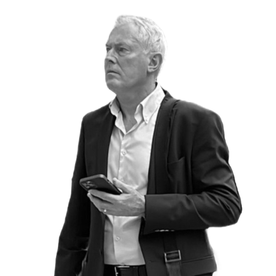 A man with gray hair in a suit holding a phone.