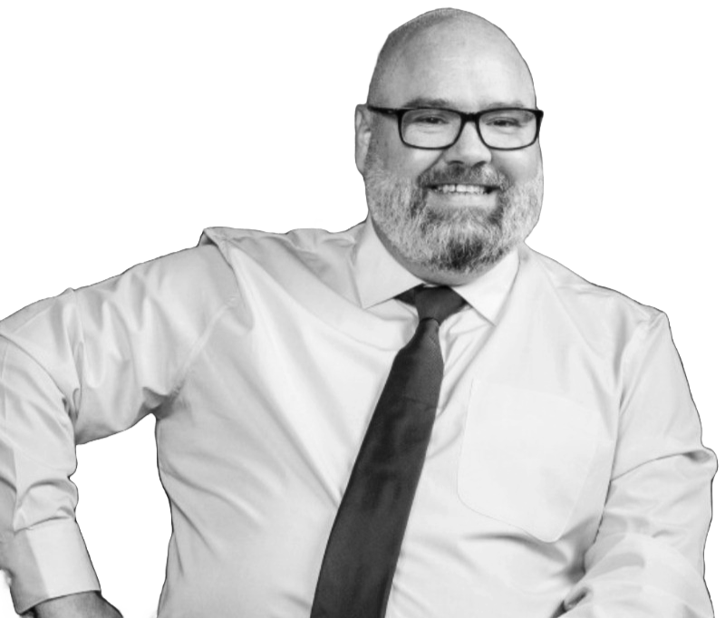 A smiling man with glasses, a beard, wearing a white shirt and tie, with his hand on his hip.
