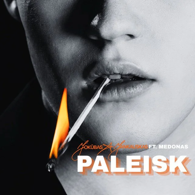 Close-up of a person's face in black and white, with lips slightly parted, holding a lit matchstick near their lips.