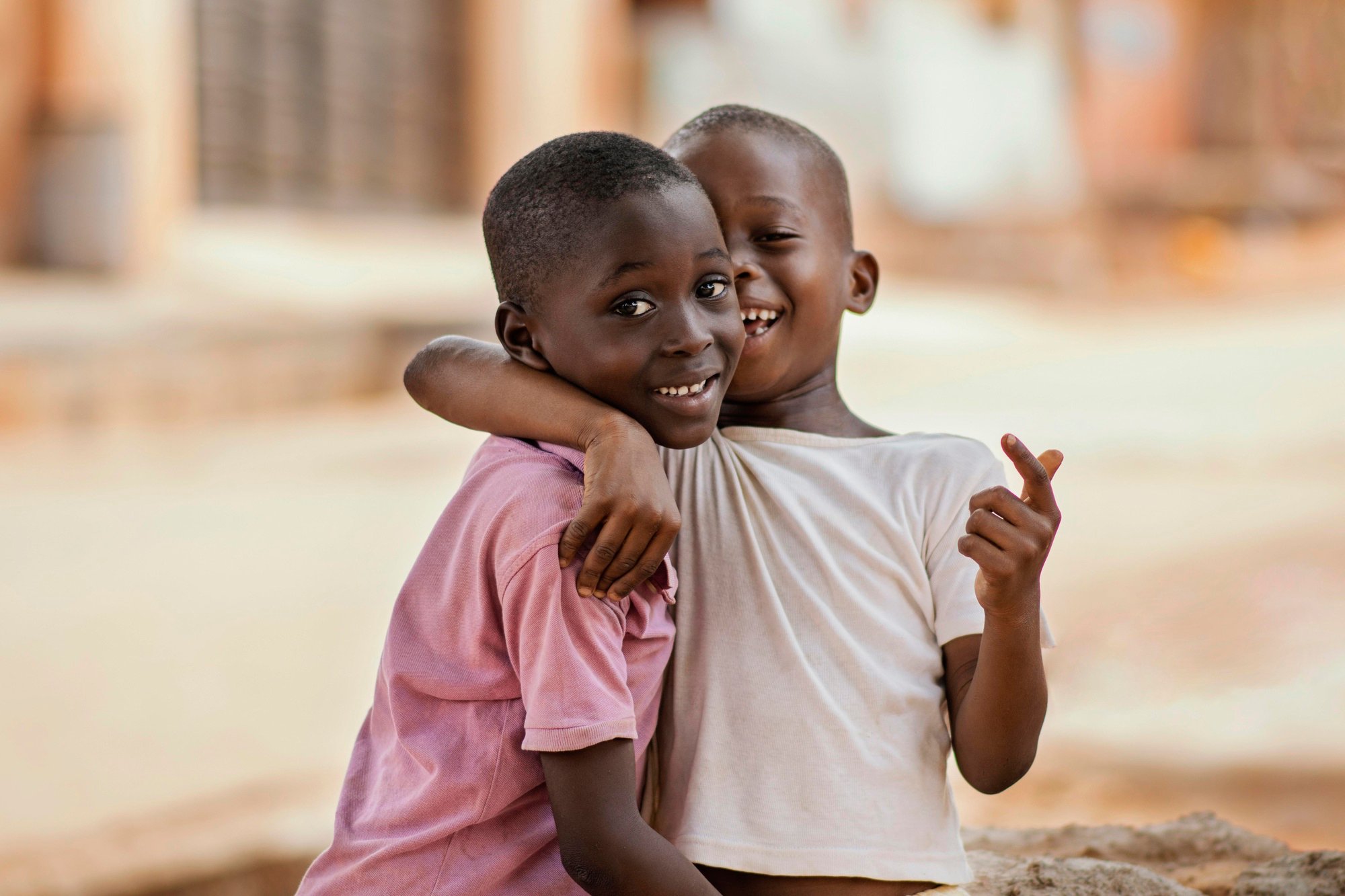 Two young boys hugging and smiling happily outdoors.