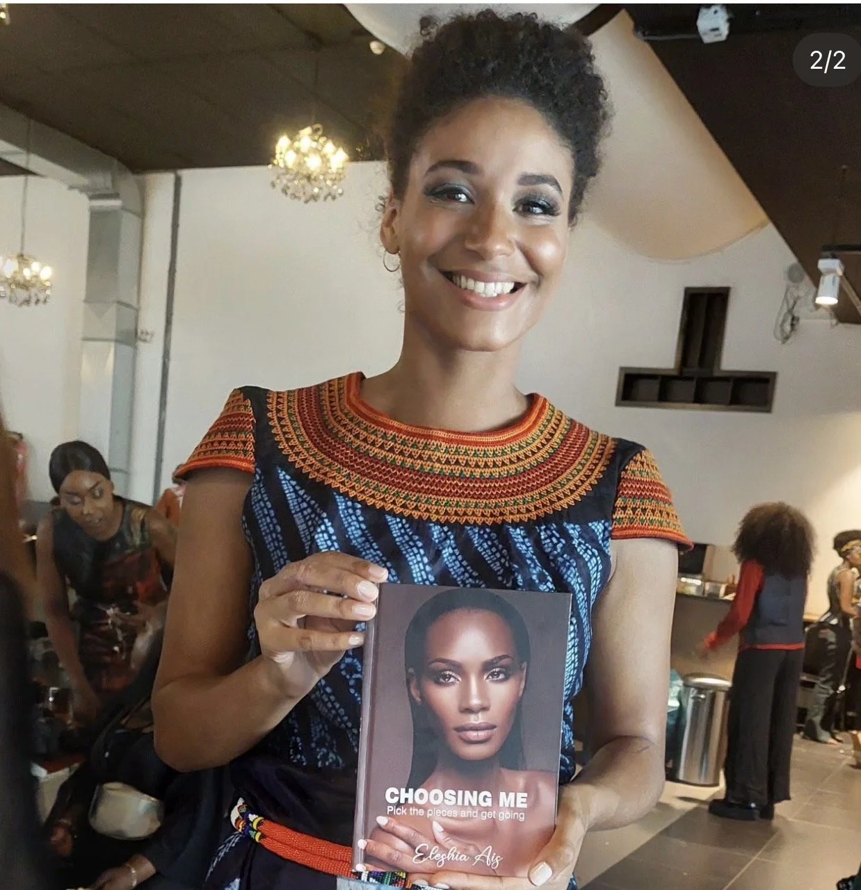 A young woman holding a book "Choosing Me" by Eleshia Ais.