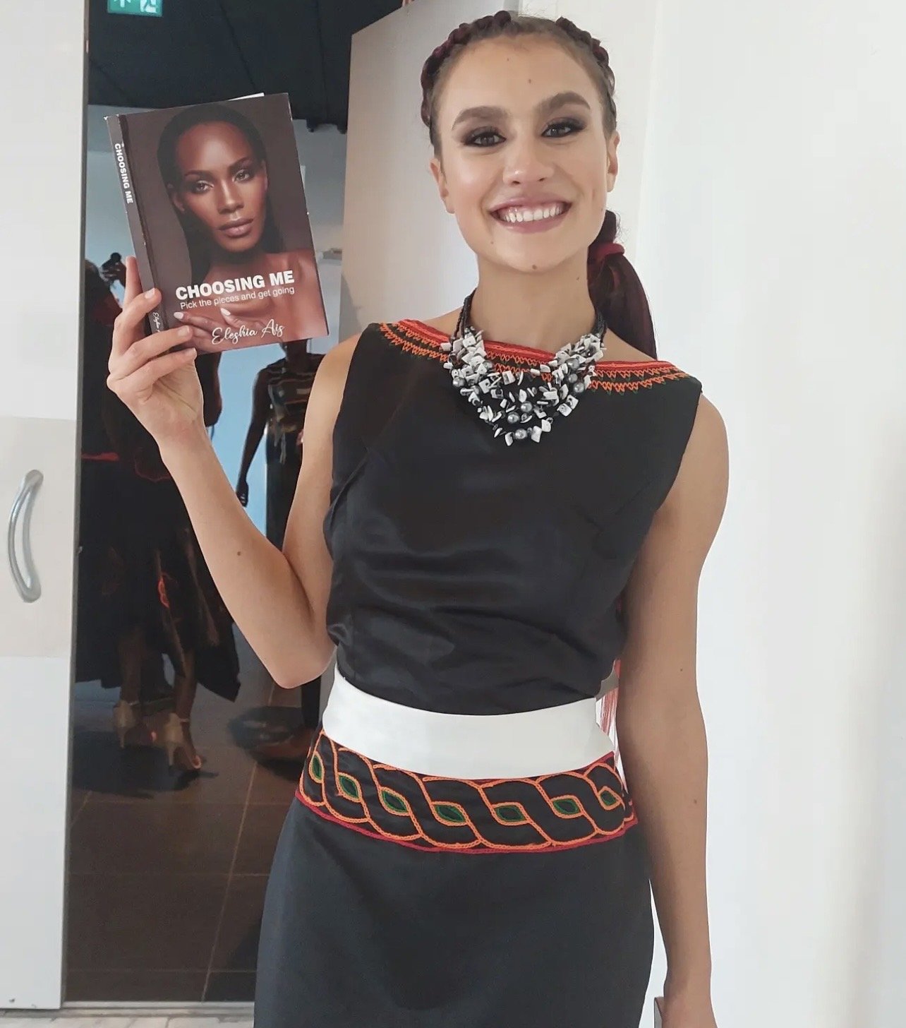 A woman with bright smile holding  'Choosing Me'  by Eleshia Ais.