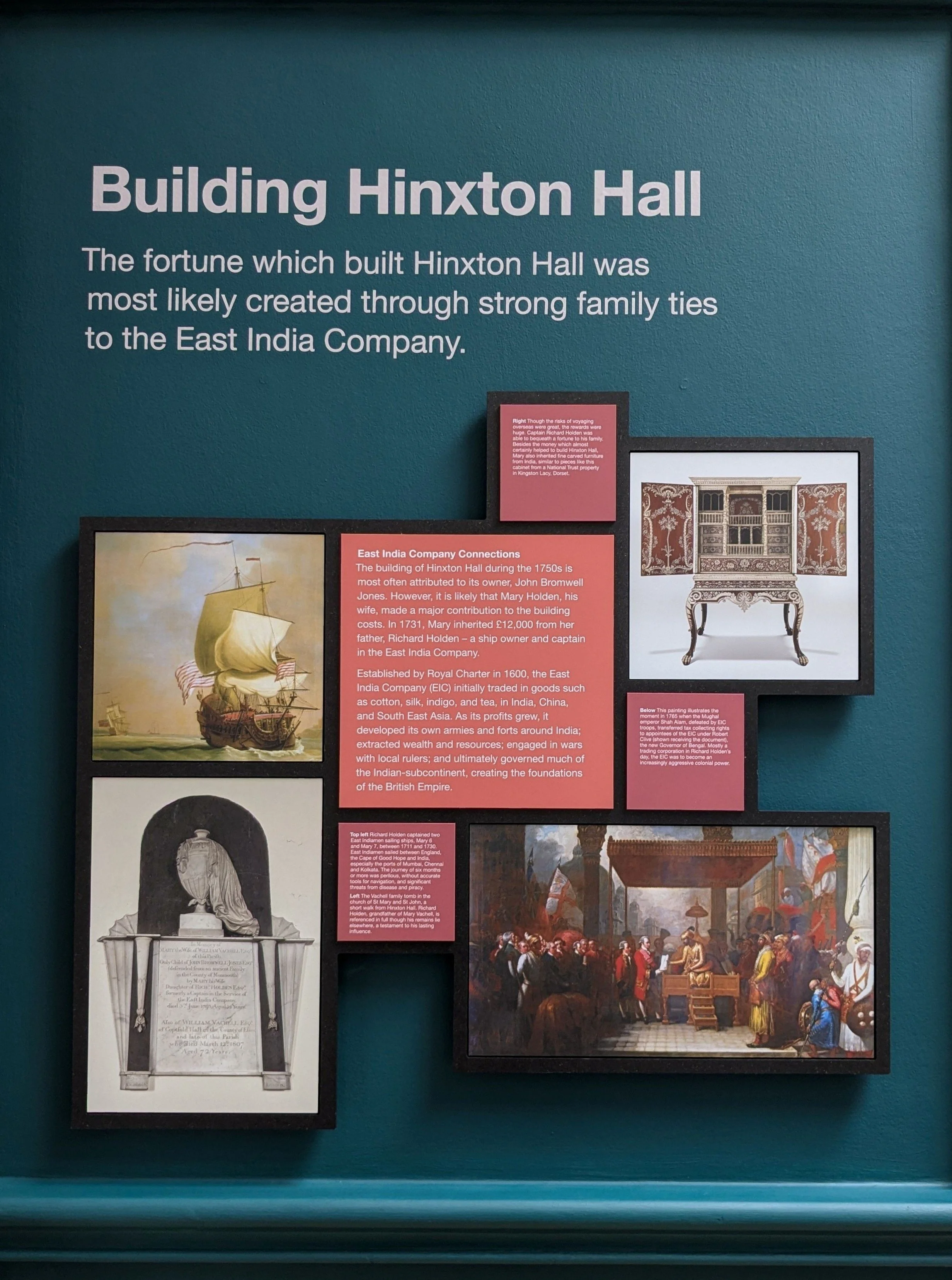 Exhibition display about the history of Hinxton Hall, featuring text panels and historical paintings, including a ship and a scene inside a grand court in India.