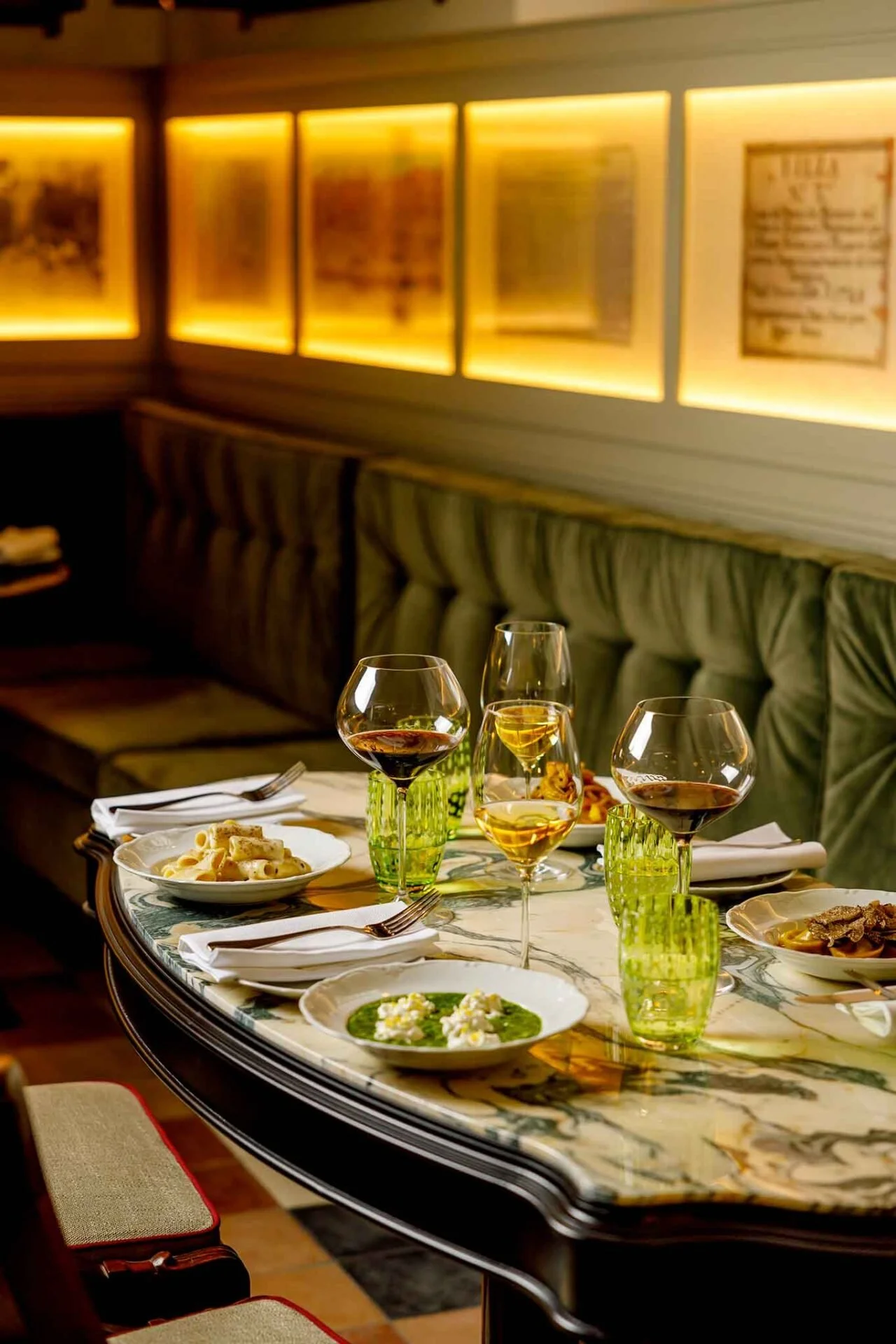 Intimate restaurant dining room with elegant table settings, wine glasses and warm ambient lighting.