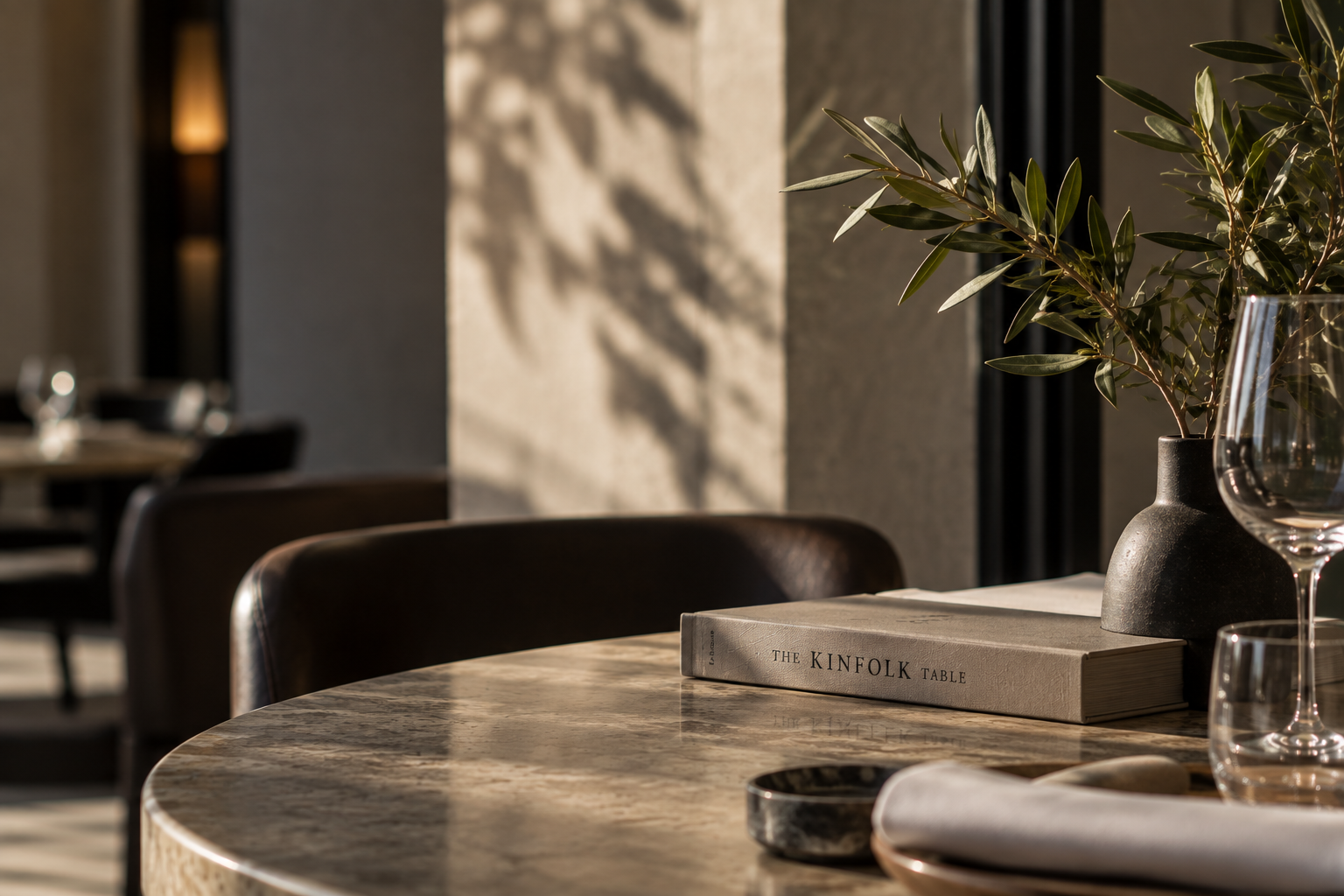 Elegant hospitality interior with a stone table, olive branches and refined decorative details in warm natural light.