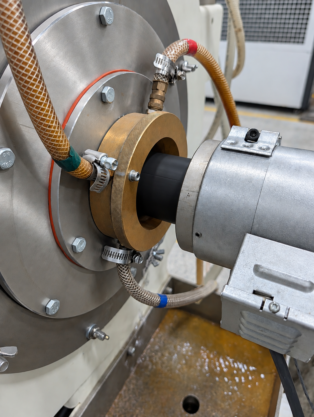 Close-up of a piece of industrial machinery with pipes, clamps, and metallic components, possibly part of a manufacturing or engineering setup.