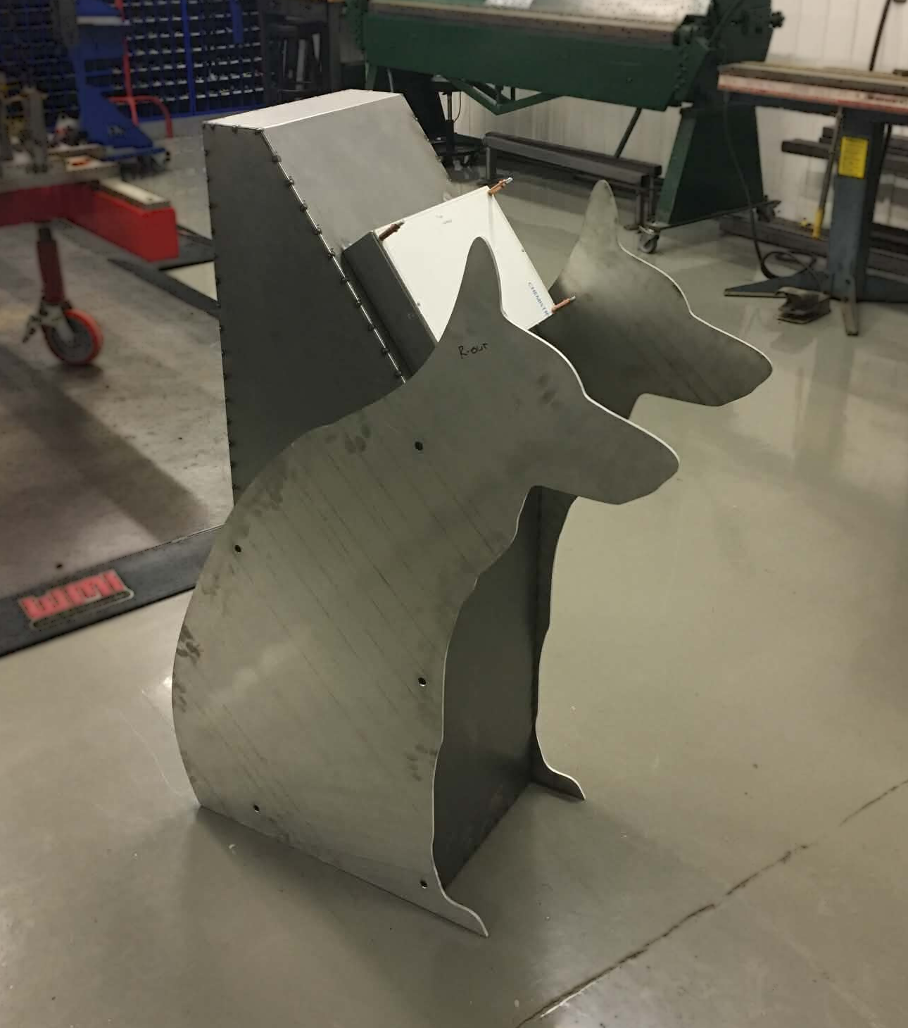 Metal sheet in the shape of a dog's head leaning against a workbench in a workshop.