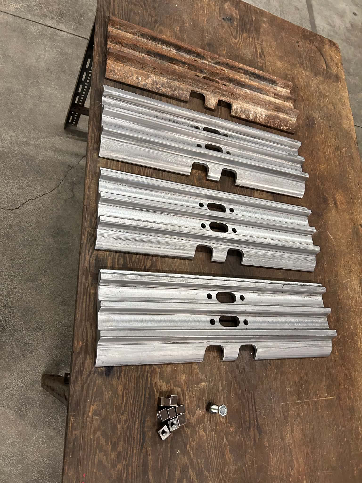 Metal rails and hardware parts on a wooden workbench.