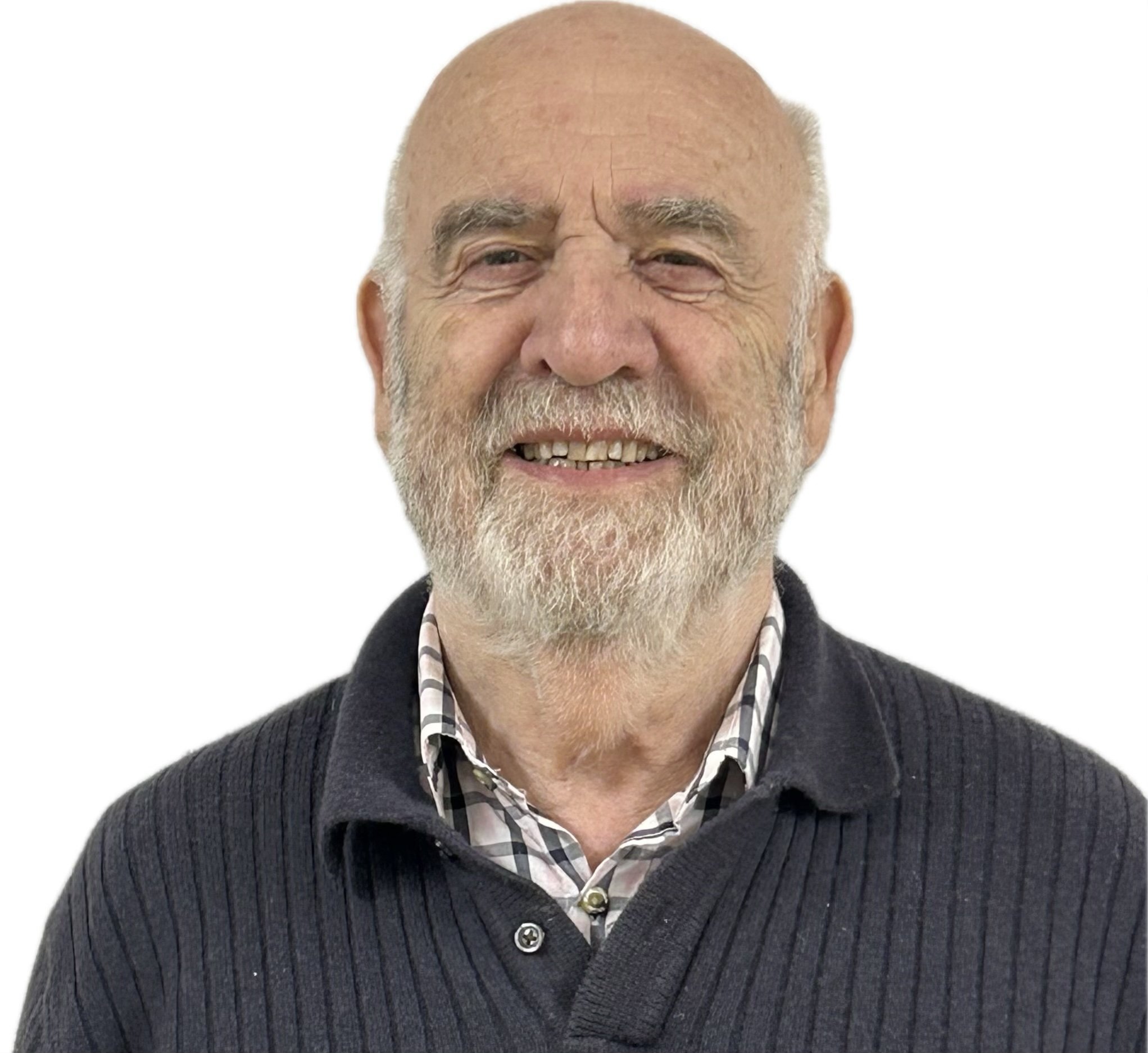 Close-up of an older man with a bald head, white beard, and smiling face, dressed in a dark sweater and a checkered shirt.