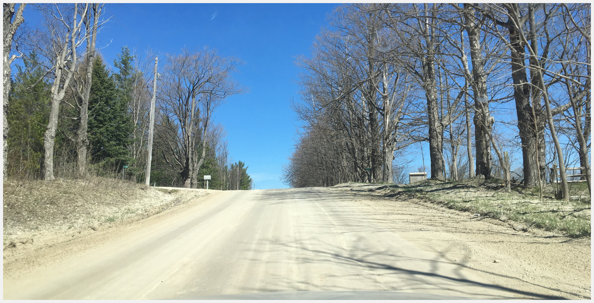 An image of a road in winter with trees on either side
