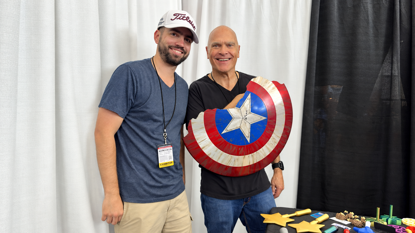 Bob Catinazzo and his son Cam holding a signed, battle-damaged Captain America shield at FanExpo Boston.