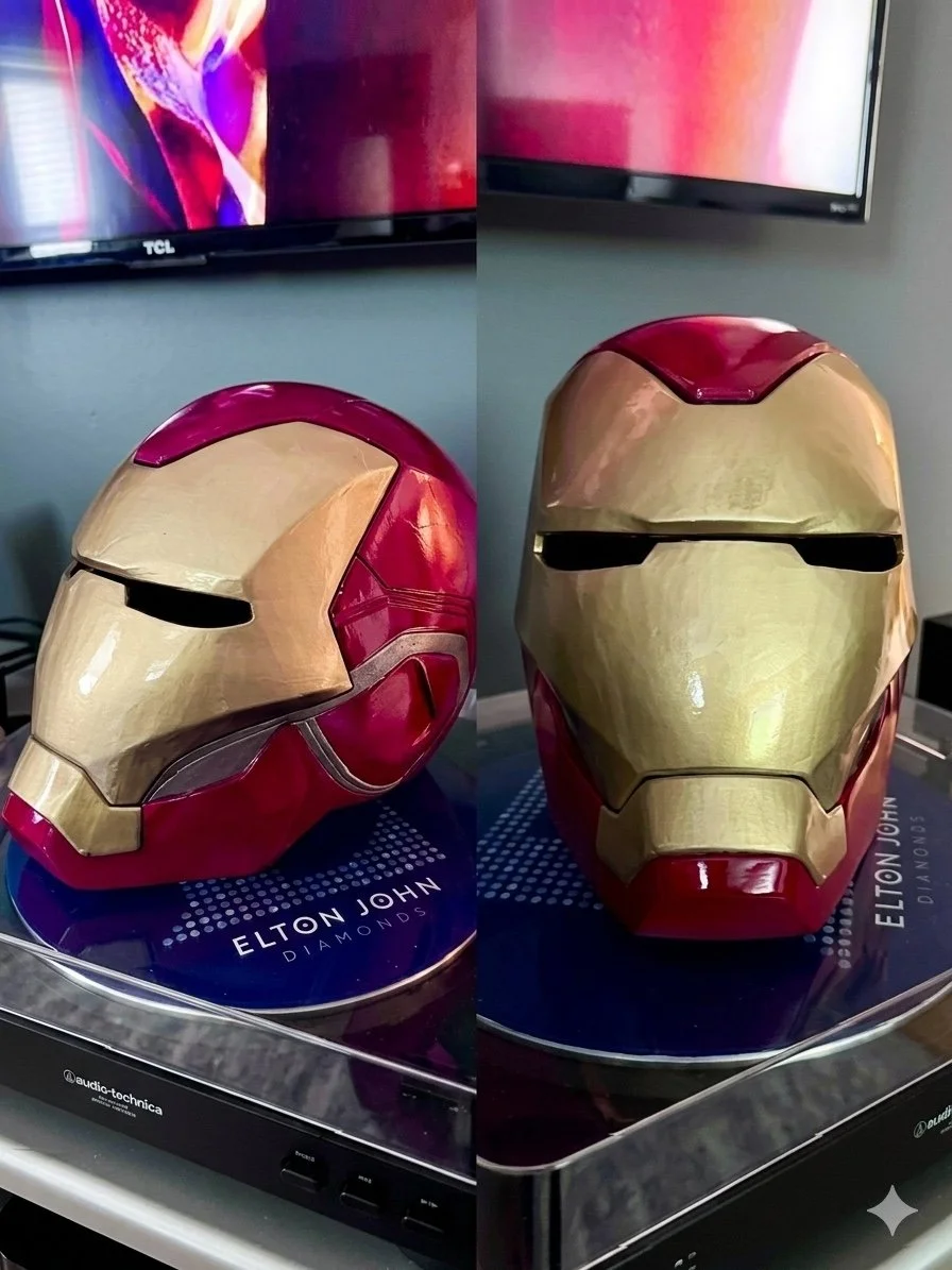 Two red-and-gold Iron Man helmets displayed on a turntable.