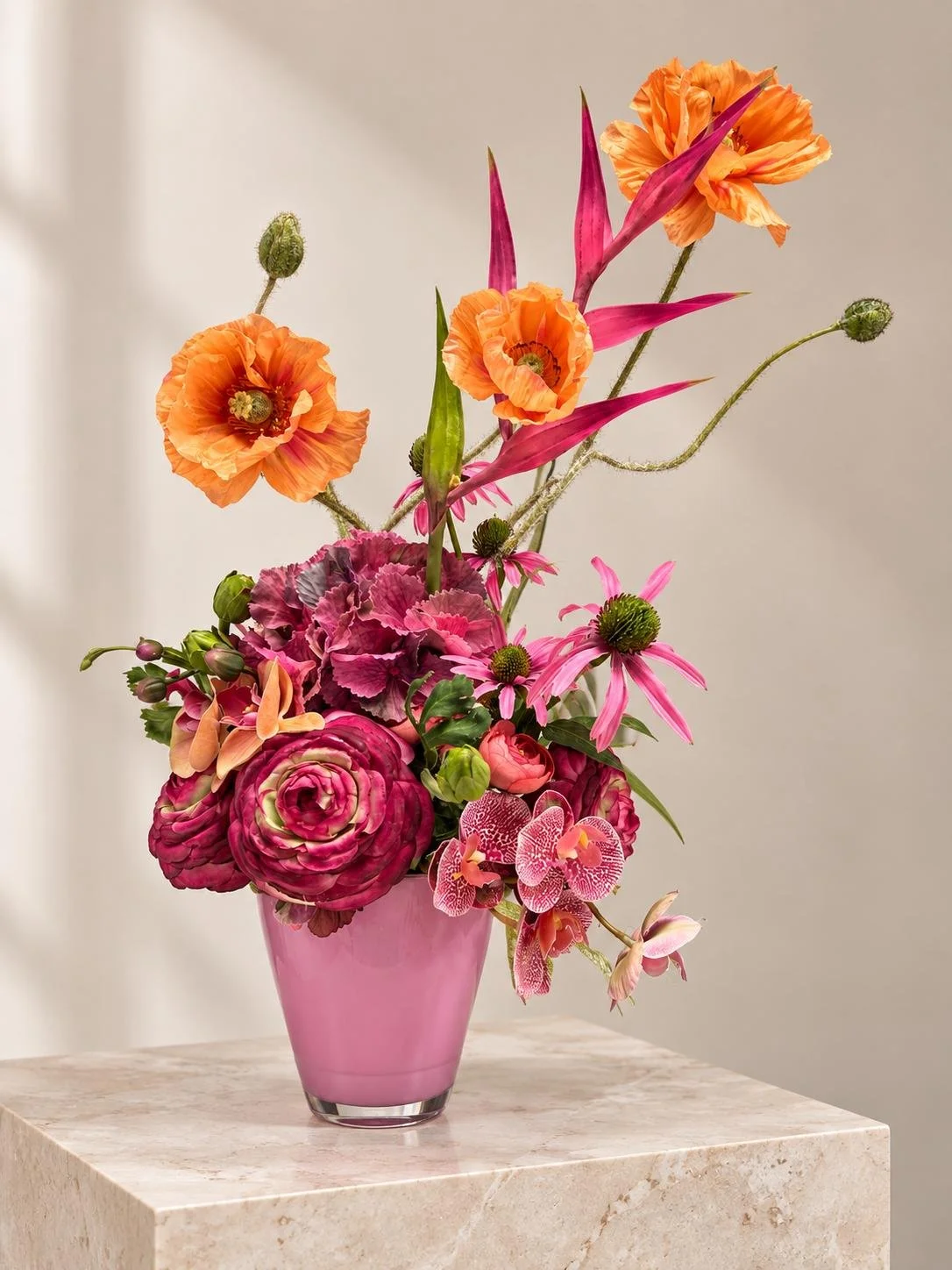 Colourful floral arrangement with pink, orange and purple seasonal flowers in a pink vase.