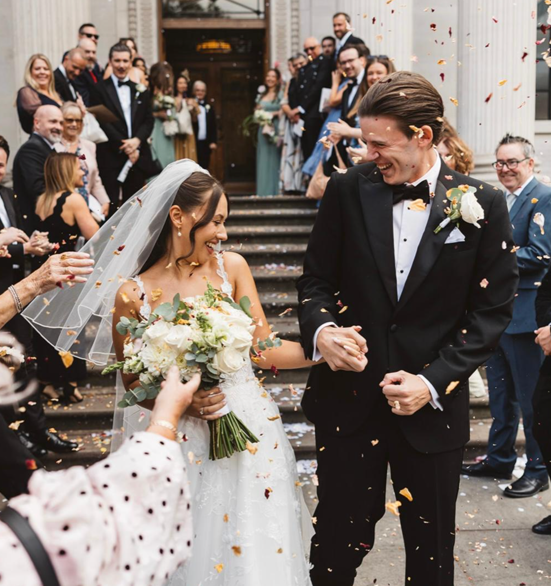 Bride and groom celebrating with guests and confetti after their wedding ceremony.