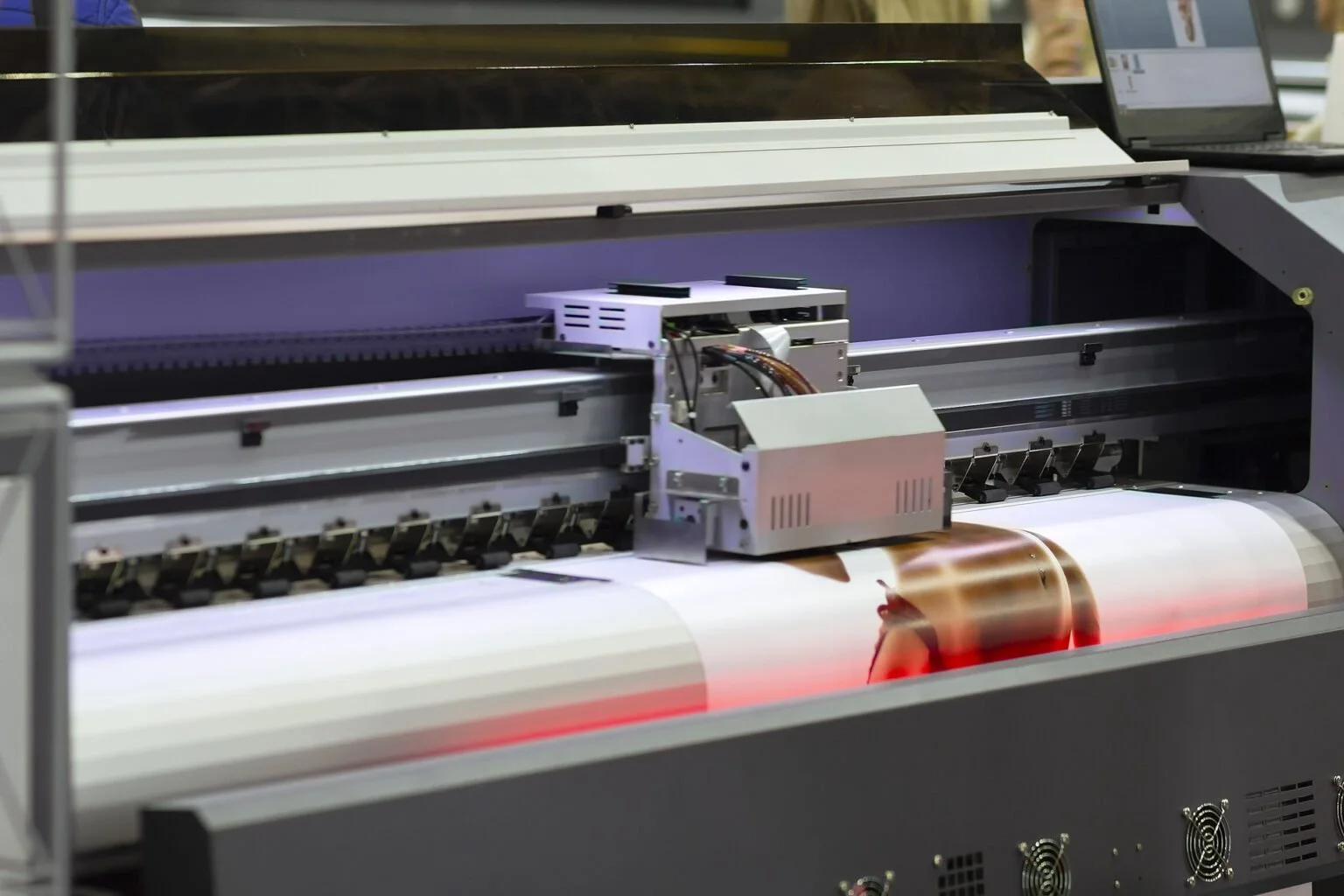 A large industrial machine printing a photograph of a woman with red hair.