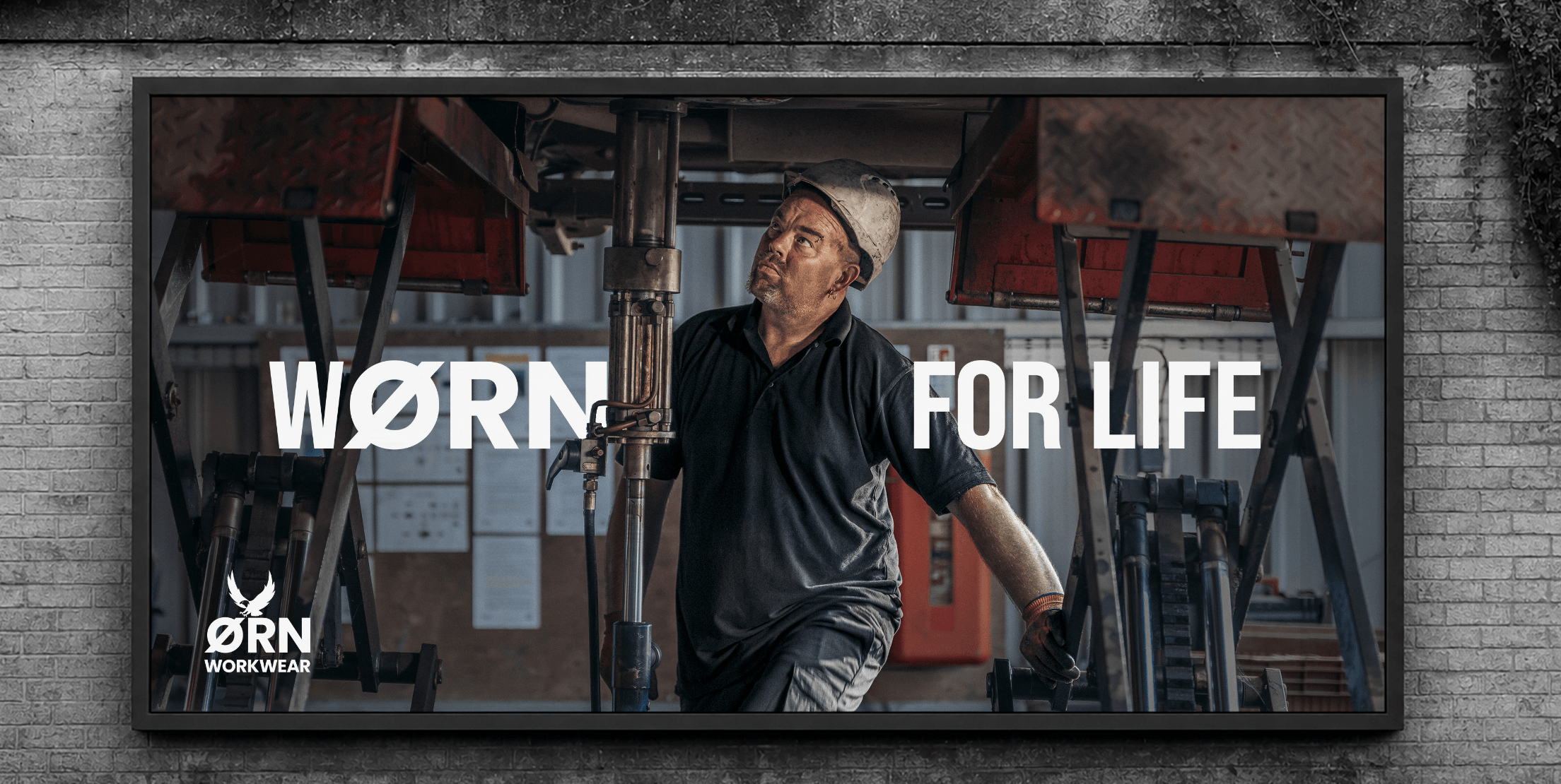 ØRN Workwear advertisement featuring a worker inspecting heavy industrial machinery with the slogan “WORN FOR LIFE.”
