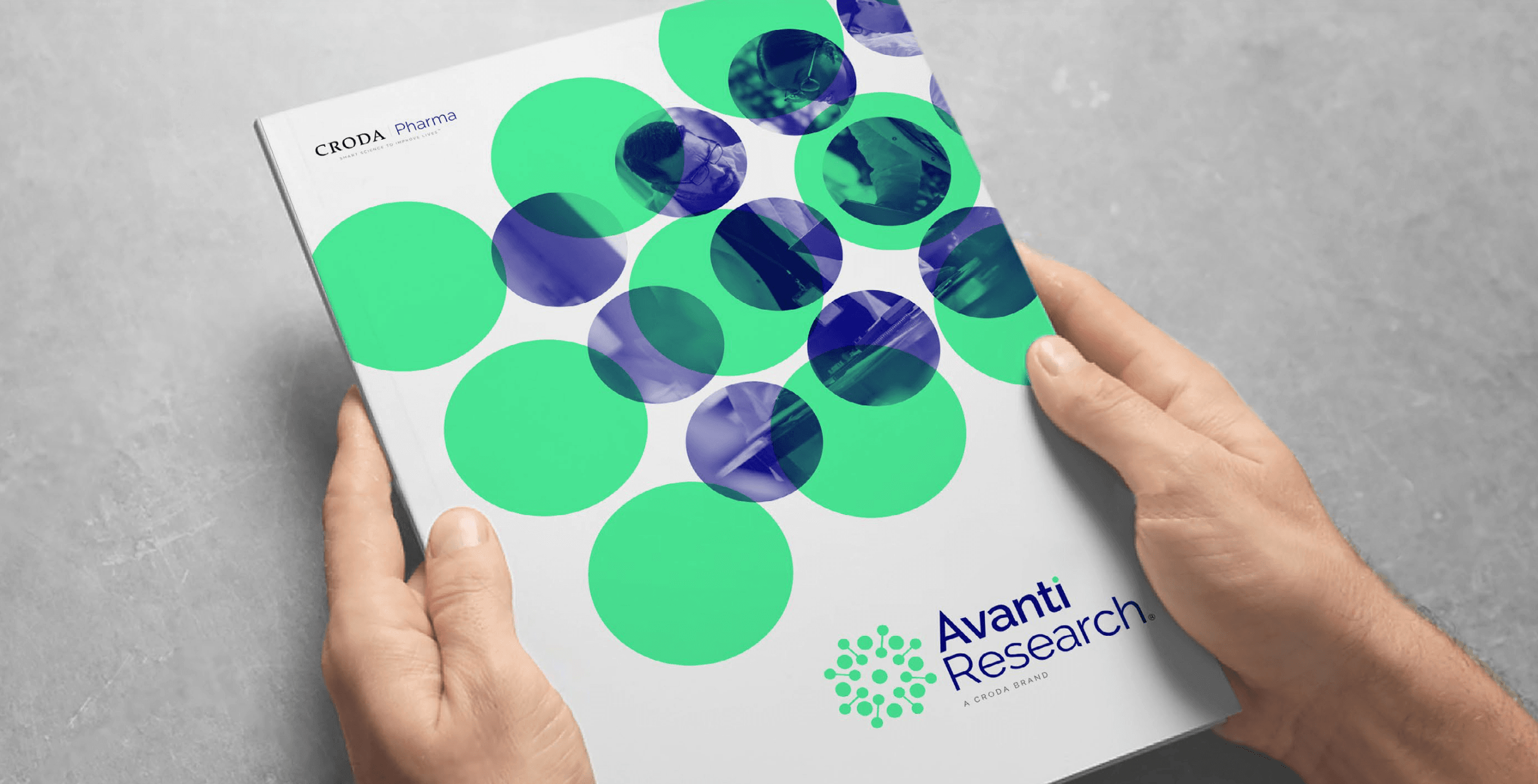 Hands holding a Croda Pharma Avanti Research brochure with green and blue circular laboratory research imagery.