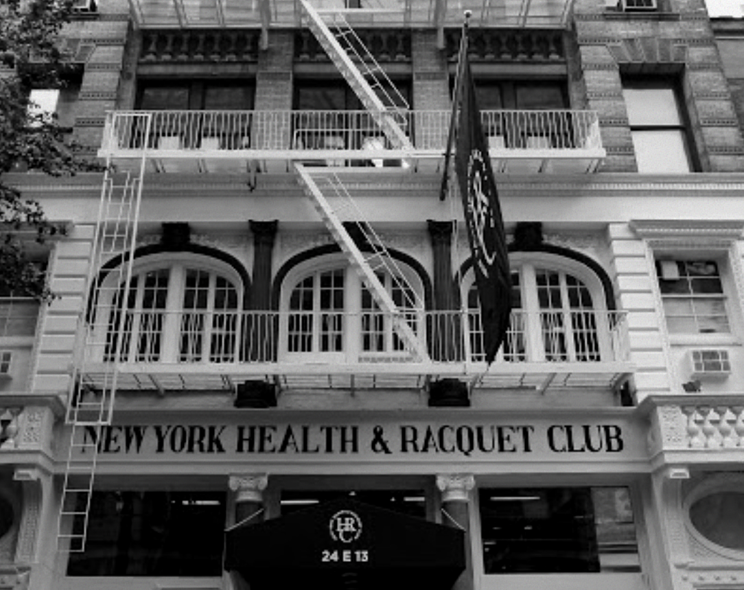 Exterior view of the New York Health & Racquet Club building, showing balconies, windows, and a flag.