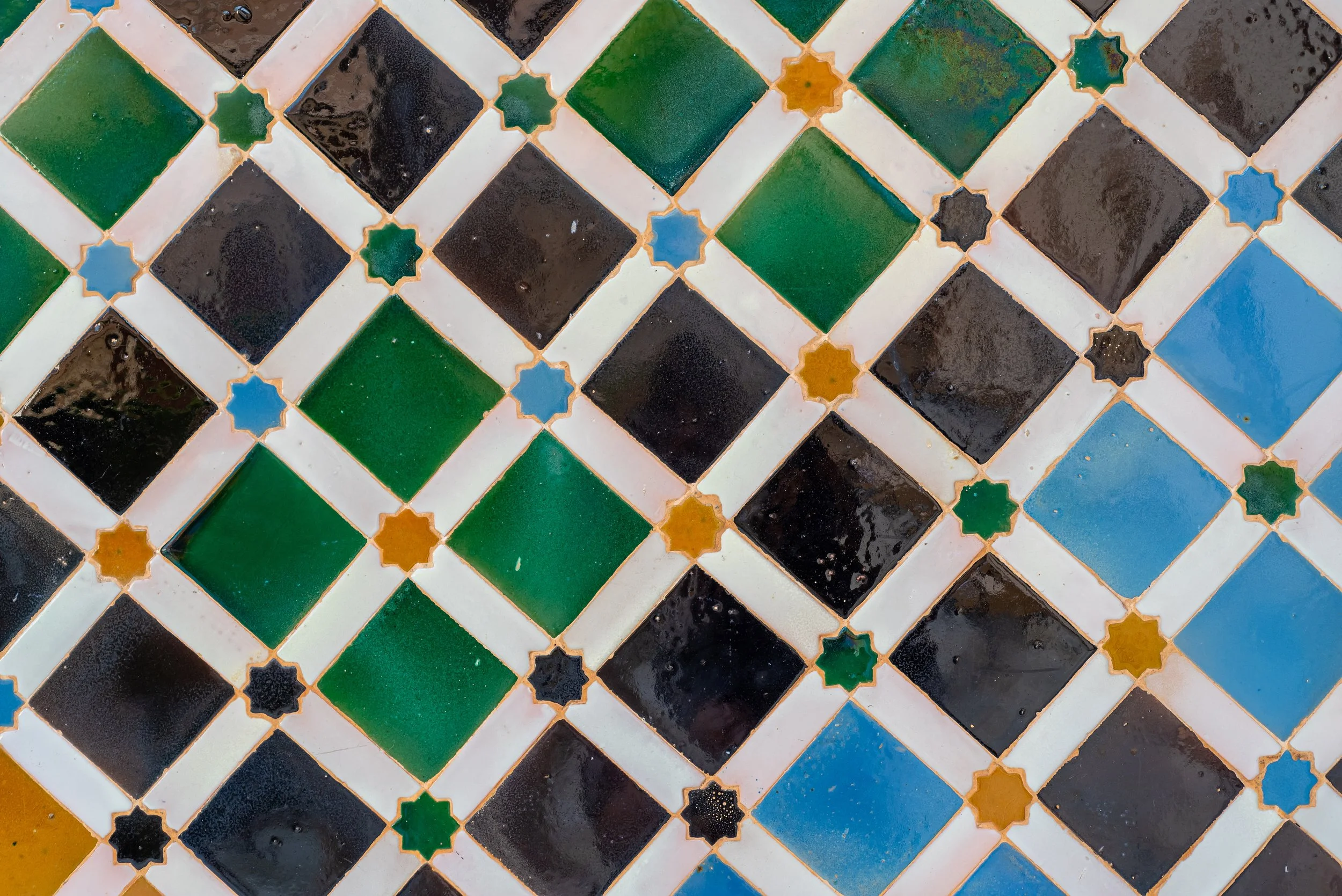 Carrelage en mosaïque avec des motifs géométriques en vert, noir, blanc, bleu et orange.