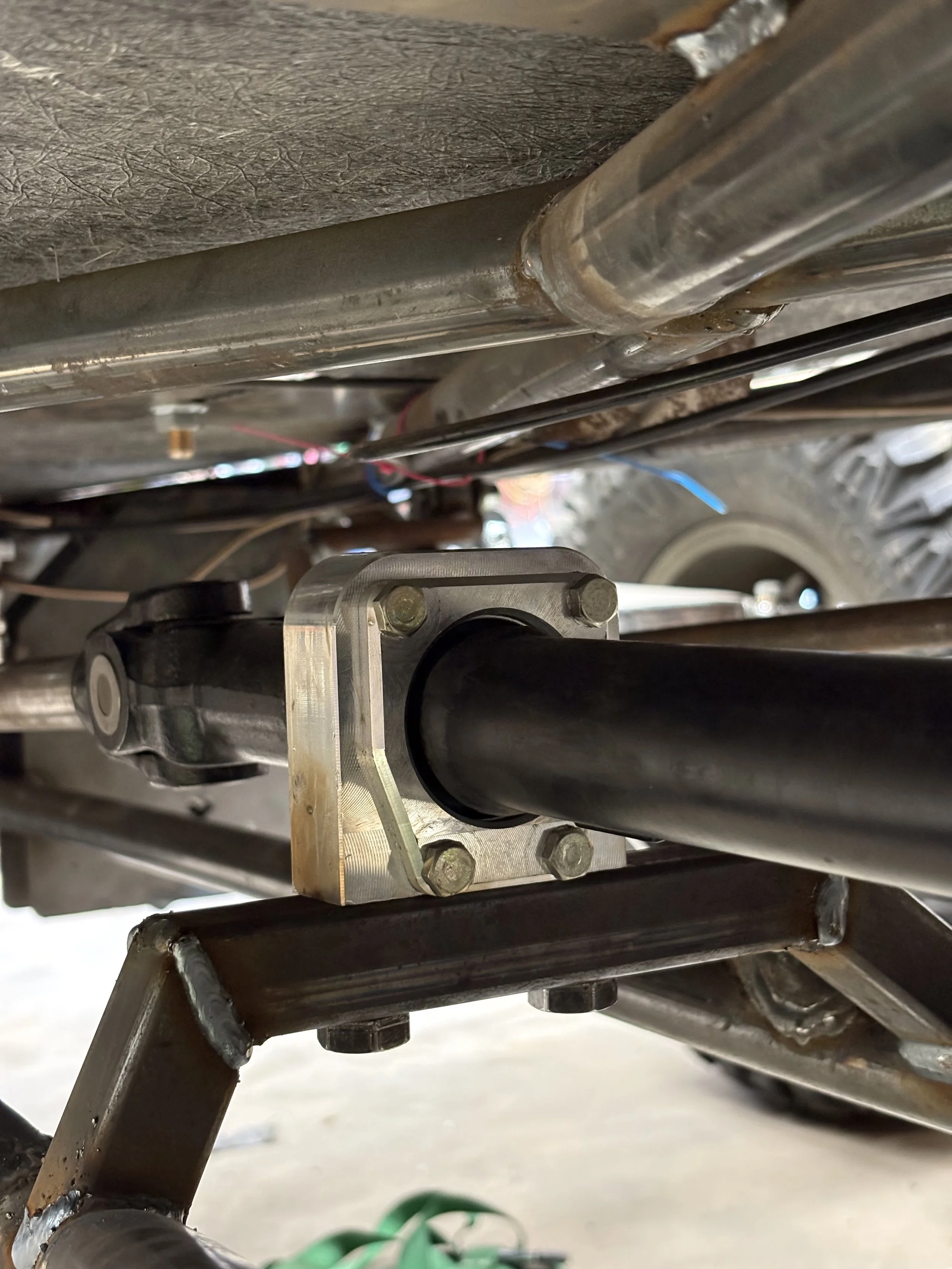Close-up view of metal tubes, bolts, and a frame structure, and a part made by a CNC milling machine.