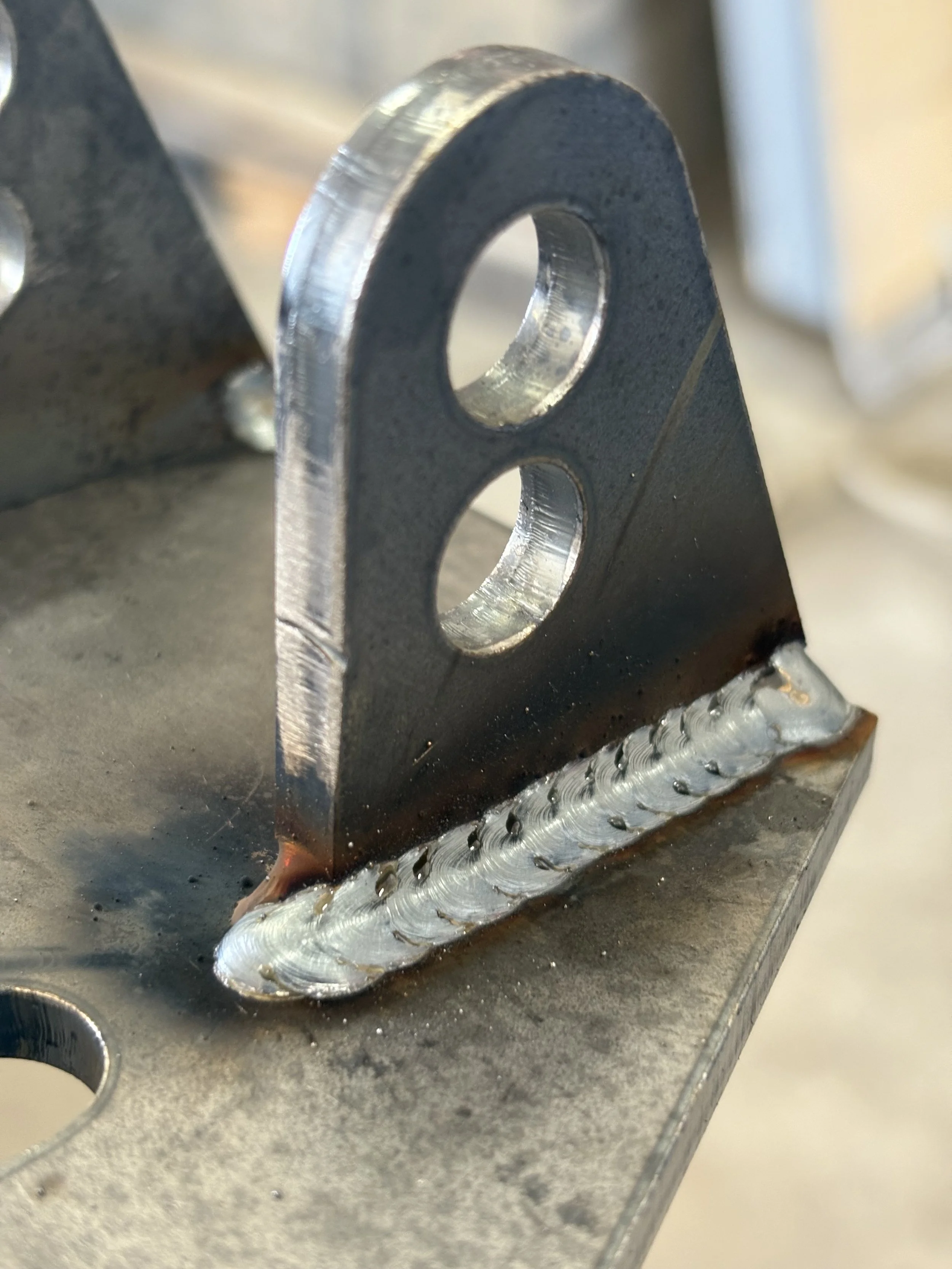 Close-up of a metal piece with a welded joint on a metal surface.