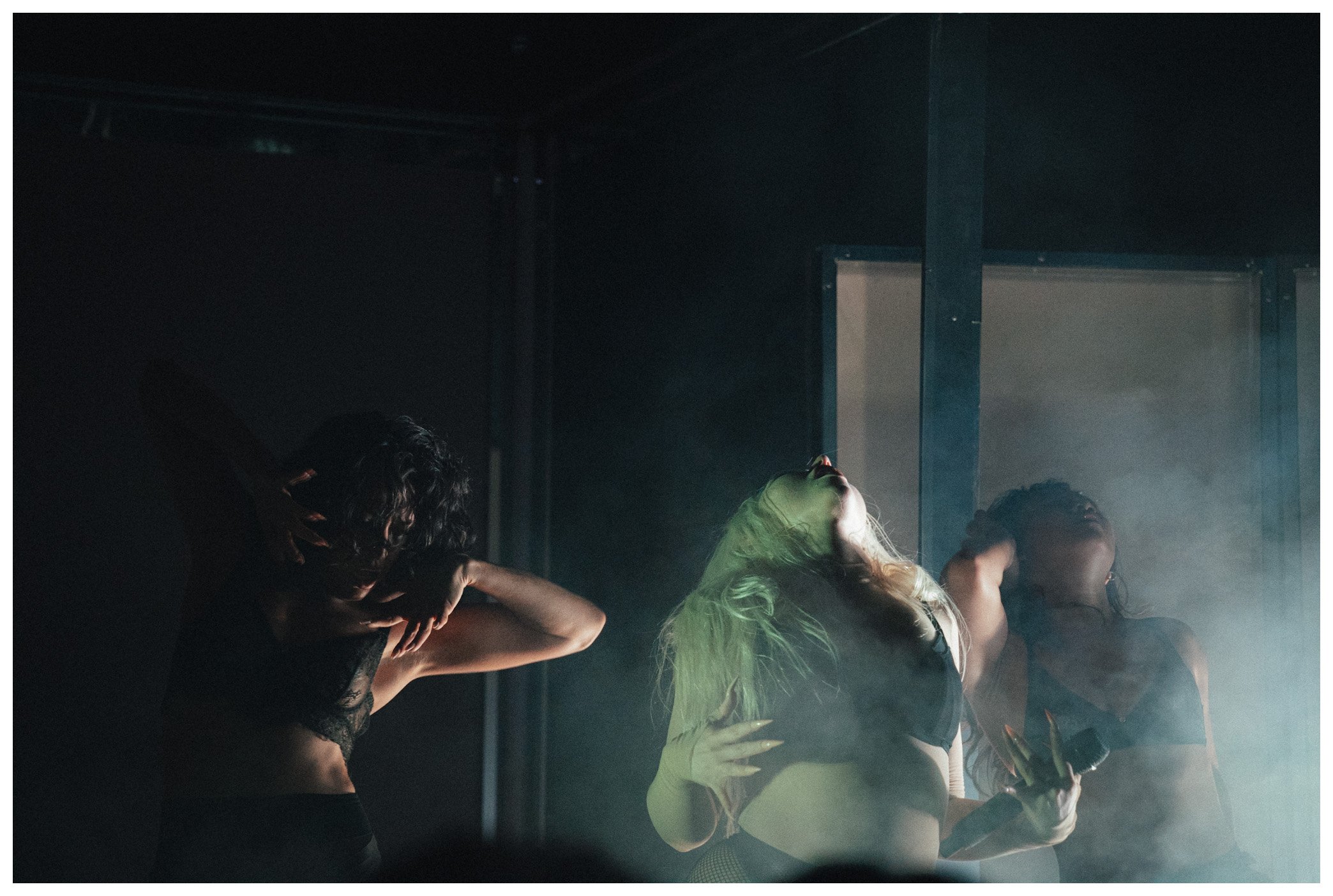 People dancing and enjoying themselves at a darkened indoor party or nightclub with fog and colorful lighting.
