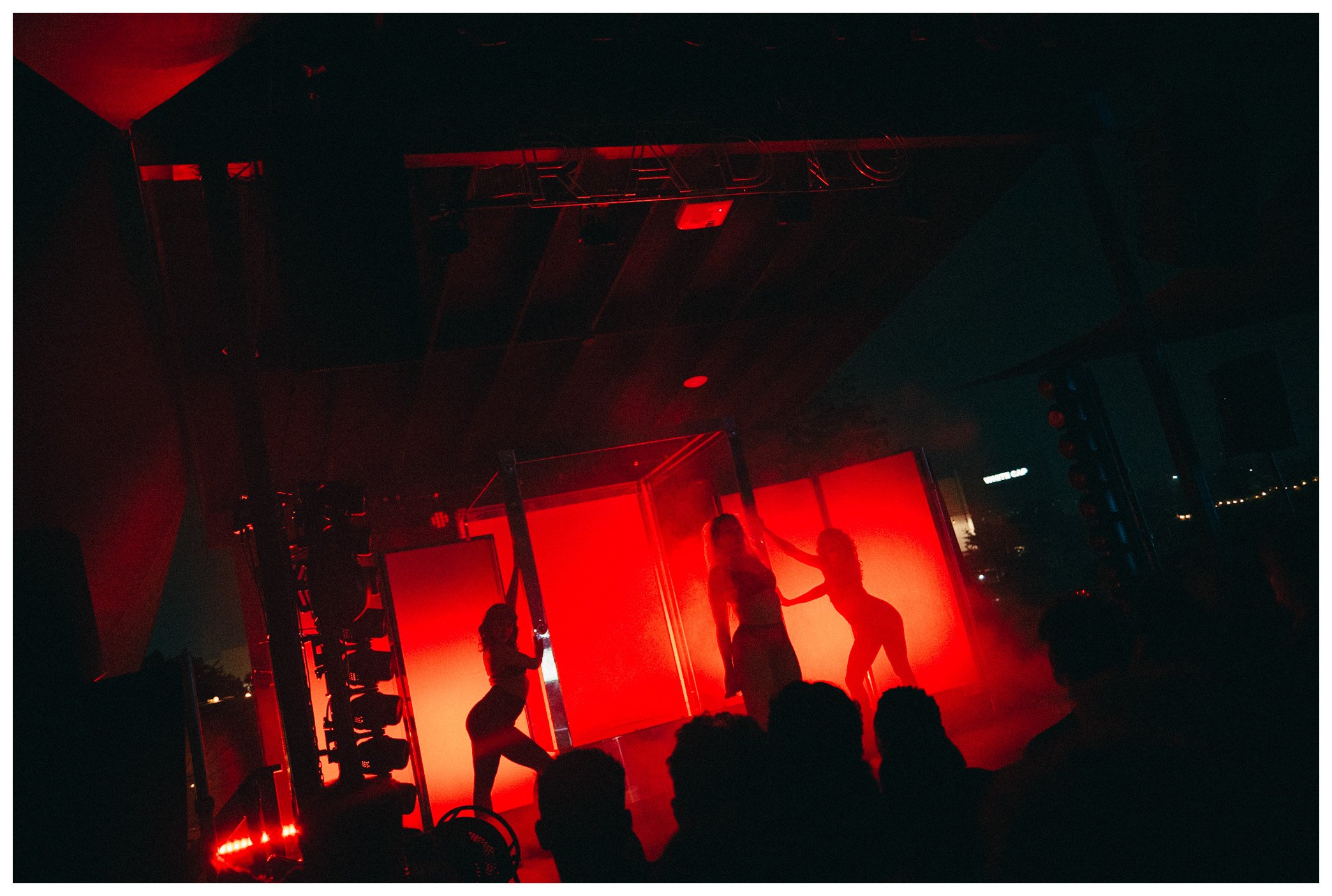 People dancing in front of a bright red backdrop at an indoor event or party.