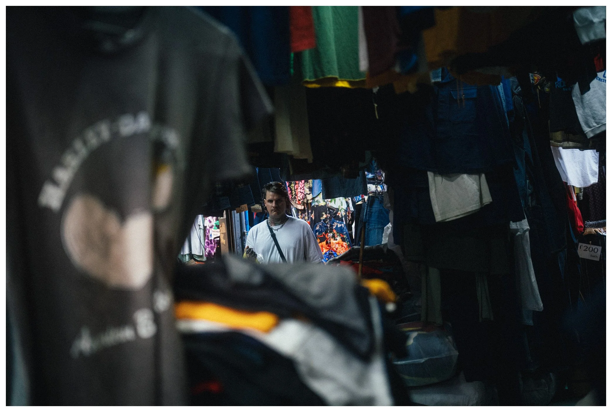 Person shopping among clothing racks at an indoor market or thrift store.