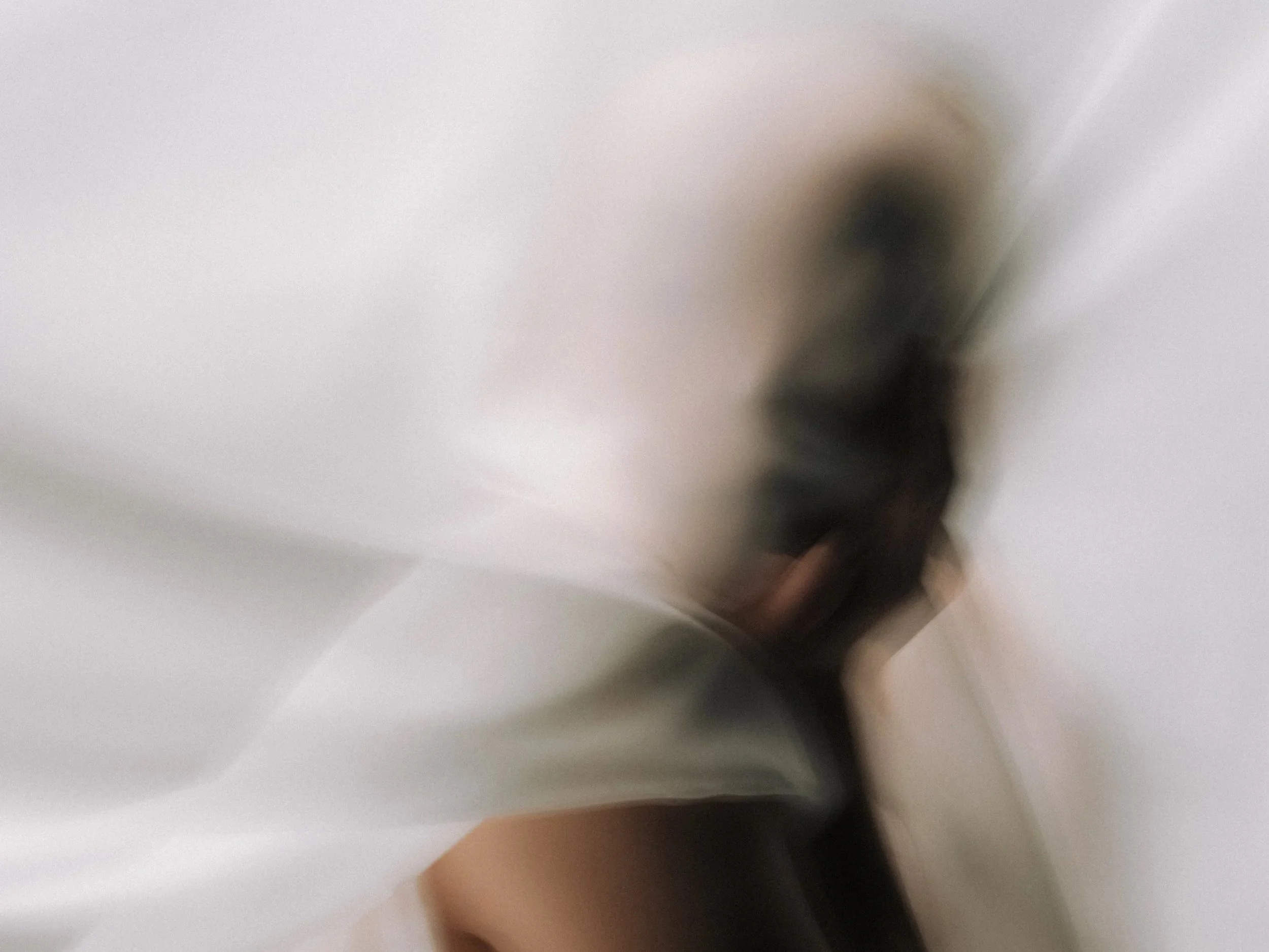 Das Bild zeigt eine verschwommene Aufnahme eines Gegenstands vor einem weißen Hintergrund, möglicherweise eine Person oder ein Objekt, das aus der Nähe fotografiert wurde.
