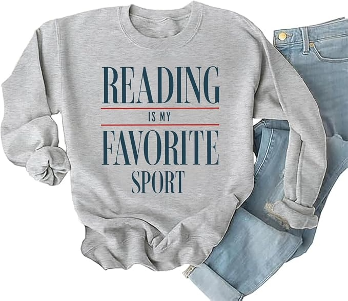 Gray bookish sweatshirt with rolled sleeves and text reading “Reading Is My Favorite Sport,” paired with distressed blue jeans; cozy, playful style.