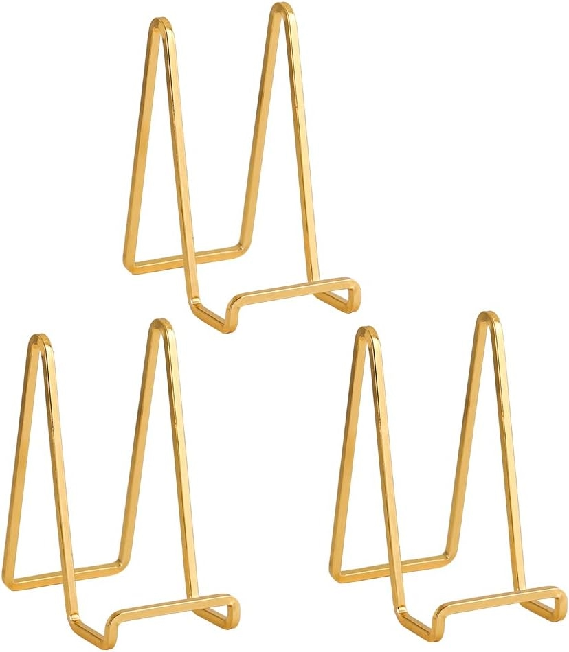 Three gold-colored wire book display stands with tall triangular loops and angled bases, arranged on a white background in a clean product image.